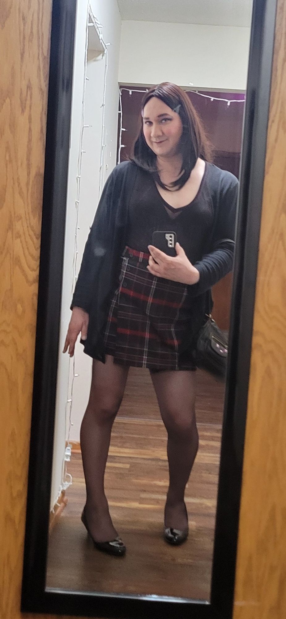 Suzies outfit: brunette hair with a black barette, sheer black and red tee shirt that says "Rock", a black bra visible beneath, a long sleeved black cardigan, short plaid pencil skirt, black tights, black high heeled pumps