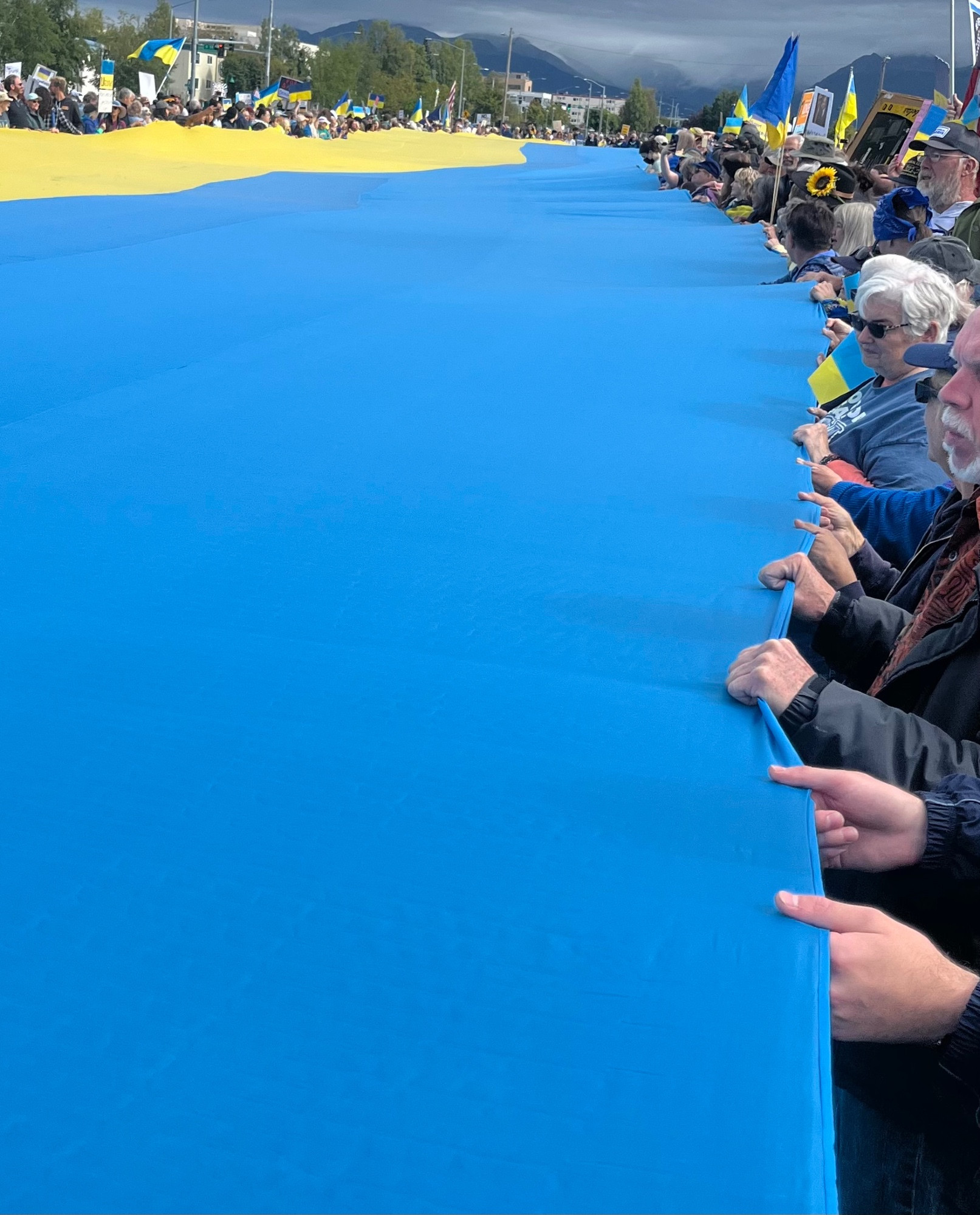 Hundred or more people holding up the huge Ukrainian flag