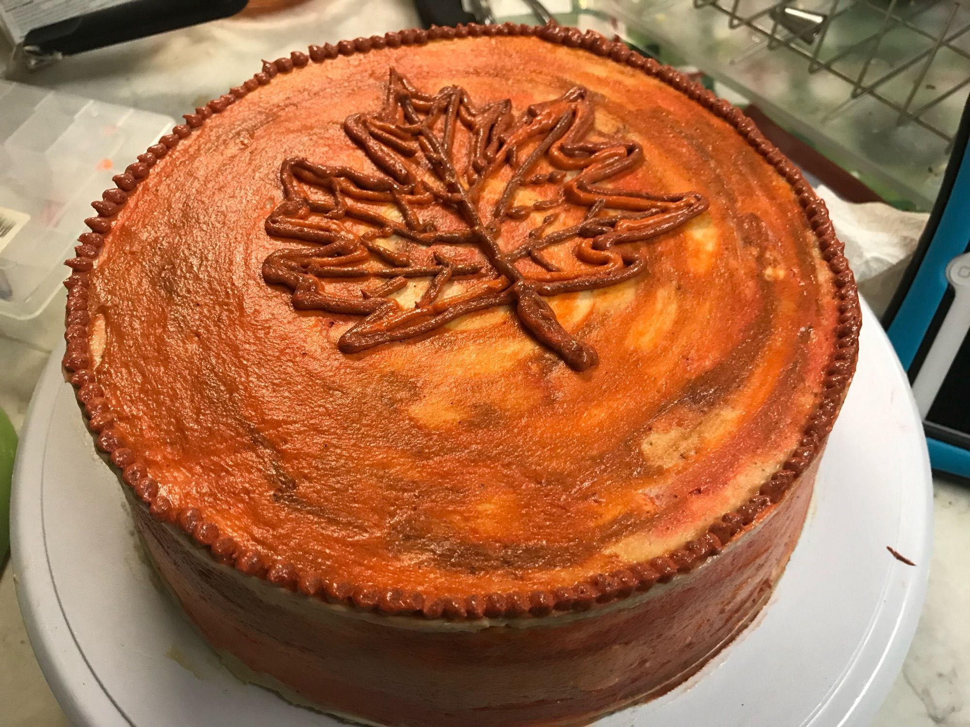 Maple brown butter cake in autumn colors with a maple leaf piped on top.