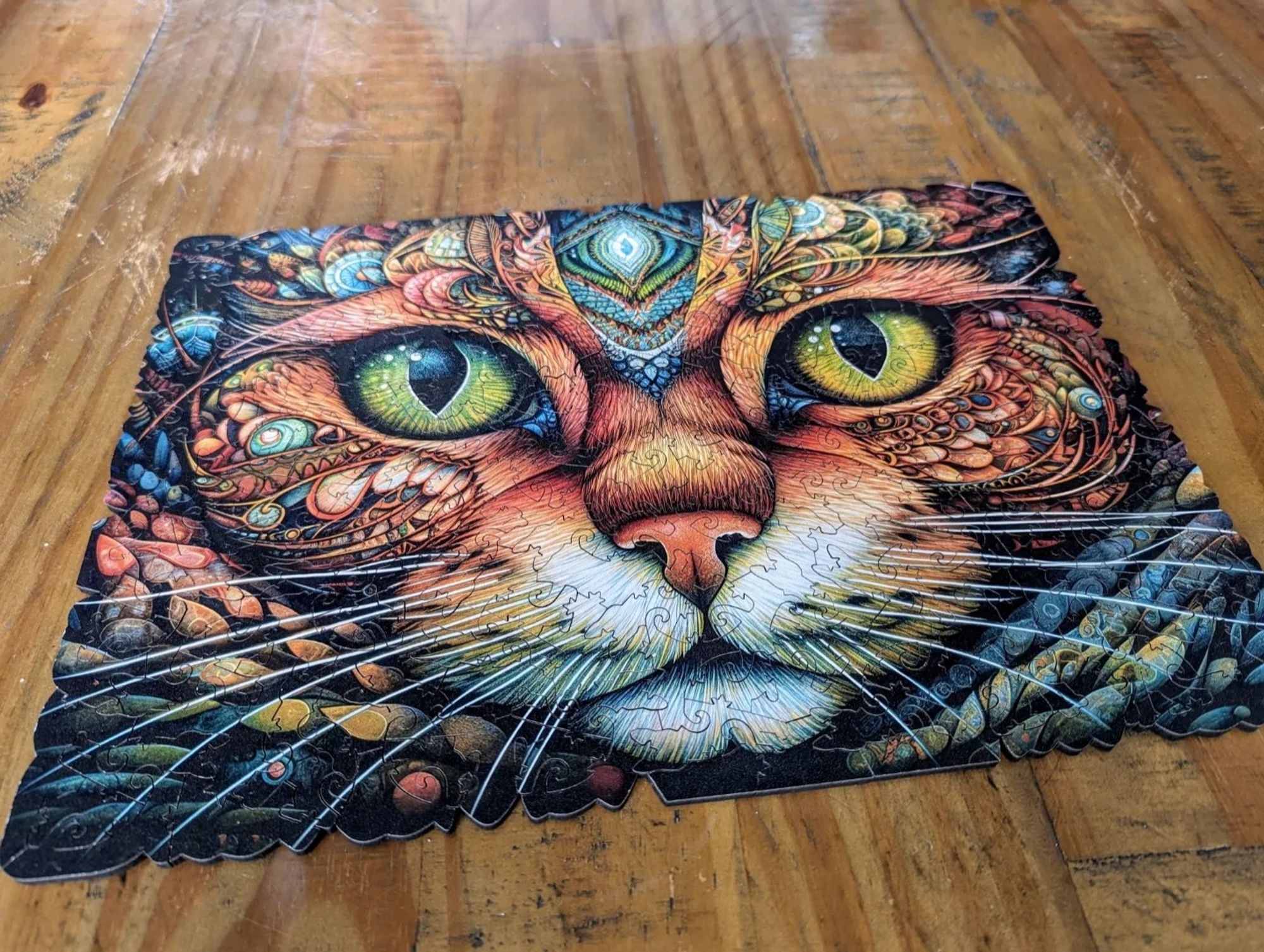 A completed jigsaw showing a very pretty, slightly abstract, image of a cat in golds, oranges, and blues