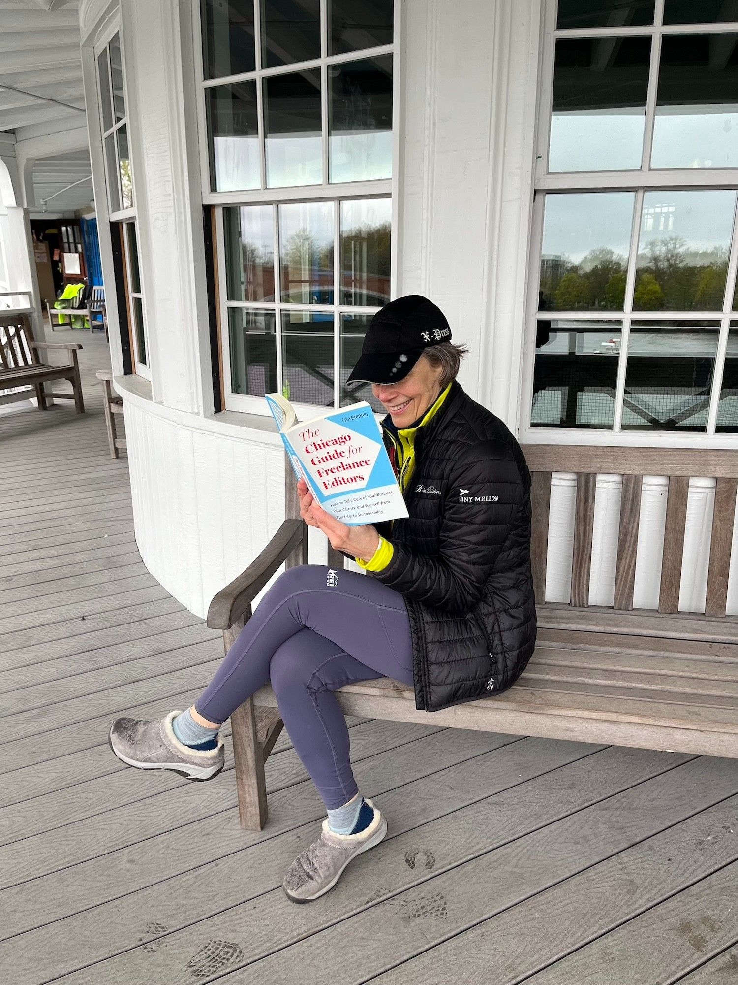 Woman sitting on a boathouse porch reading Chicago Guide for Freelance Editors