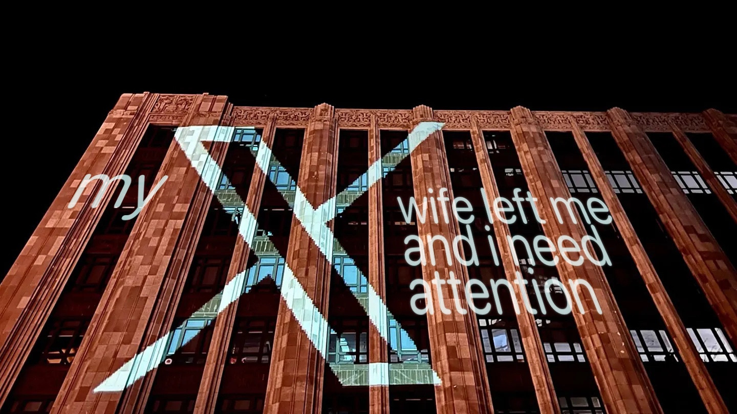 Twitter building at night with words projected on it: “My X wife left me and I need attention.”