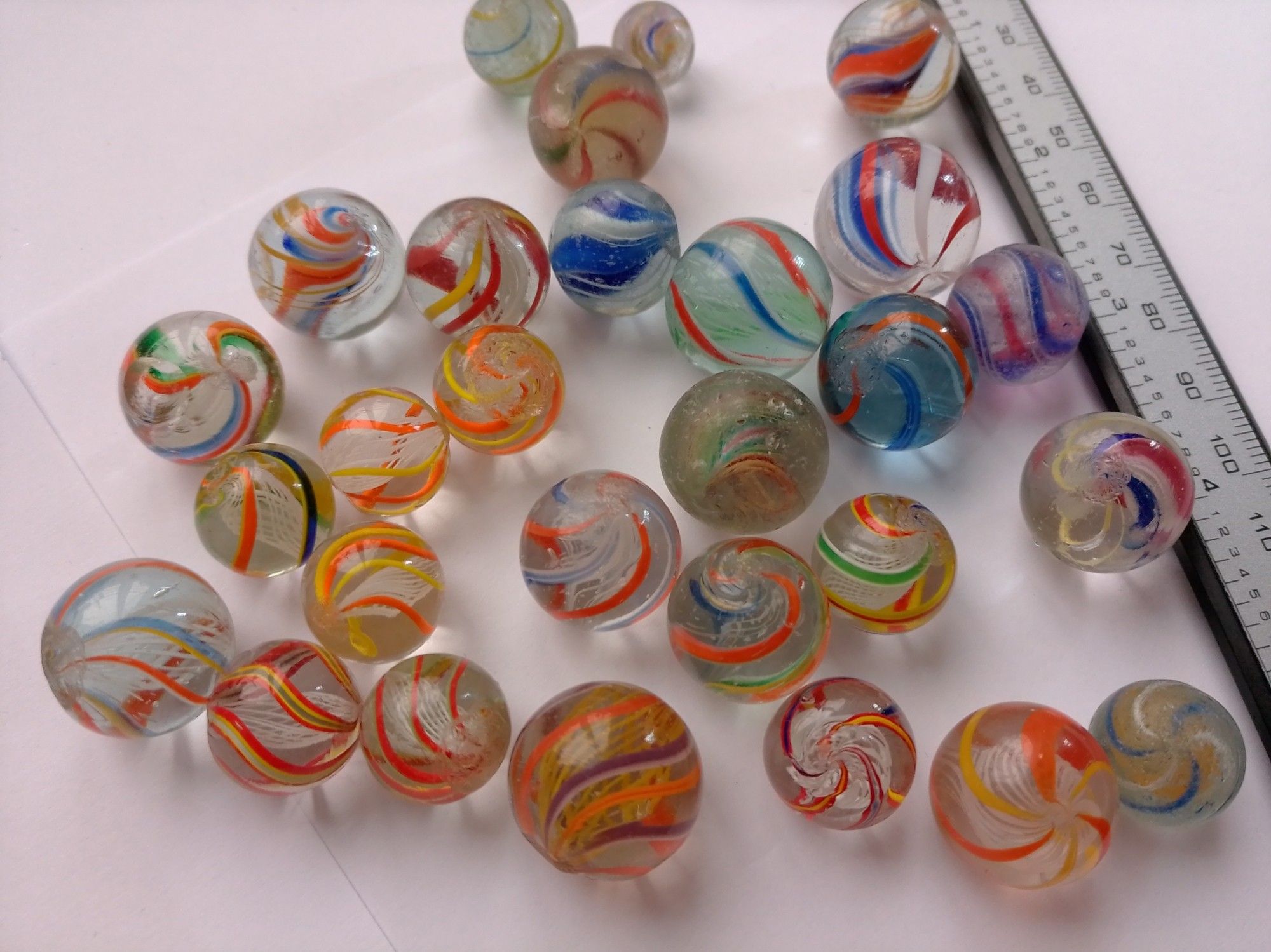 A group of vintage german hand made glass marbles, most of them latticinio core with colorful ribbons on the outside