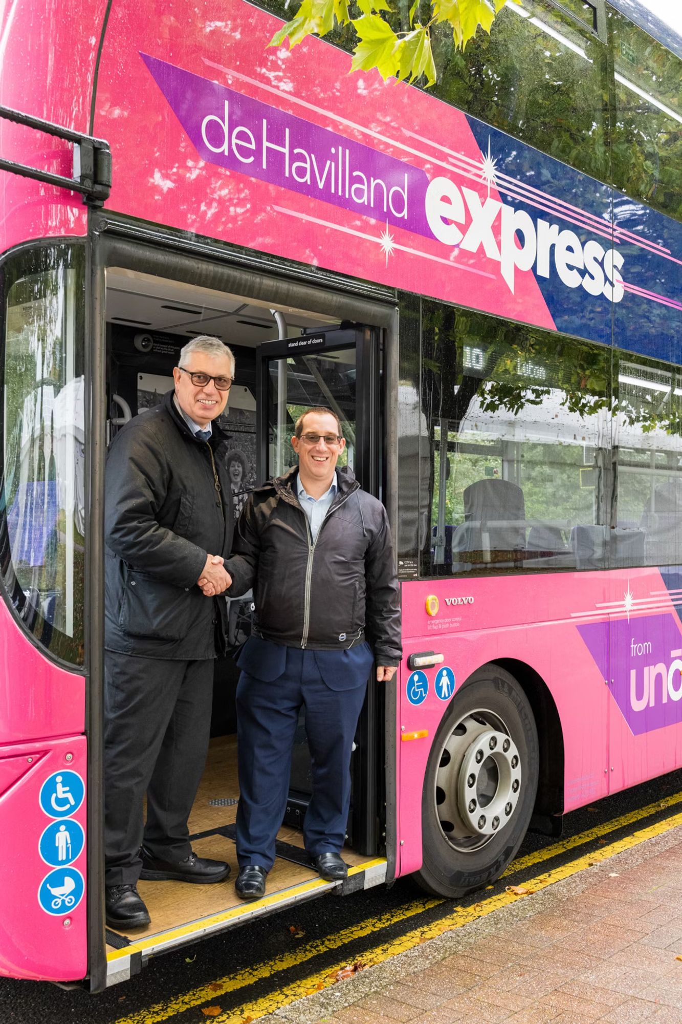 Two individuals shaking hands at the entrance of a de Havilland express bus.

Photo by Volvo