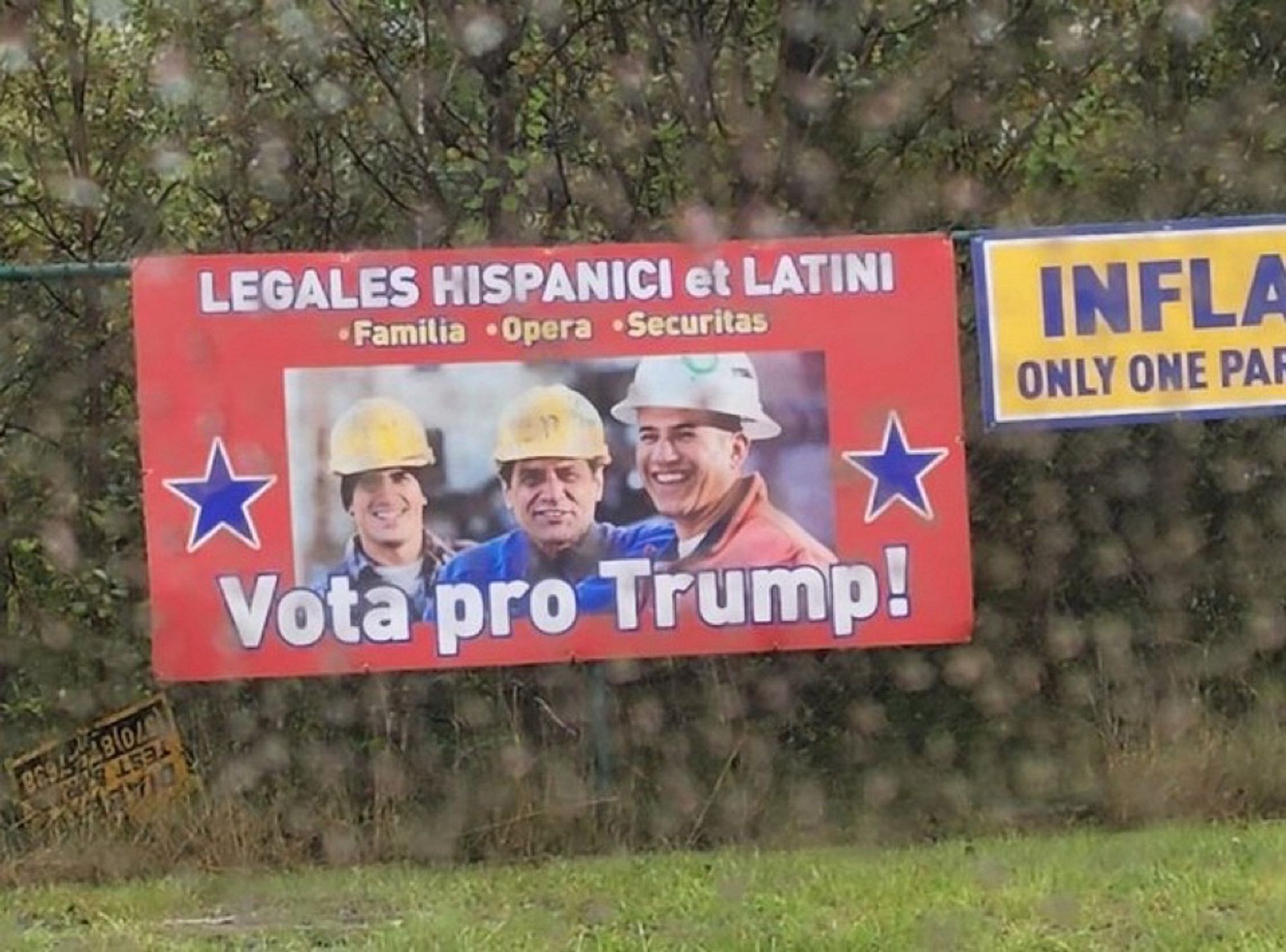 A big banner sign with smiling men in hard hats on it reading “LEGALES HISPANICI et LATINI

*Familia *Opera *Securitas

VOTA PRO TRUMP!”