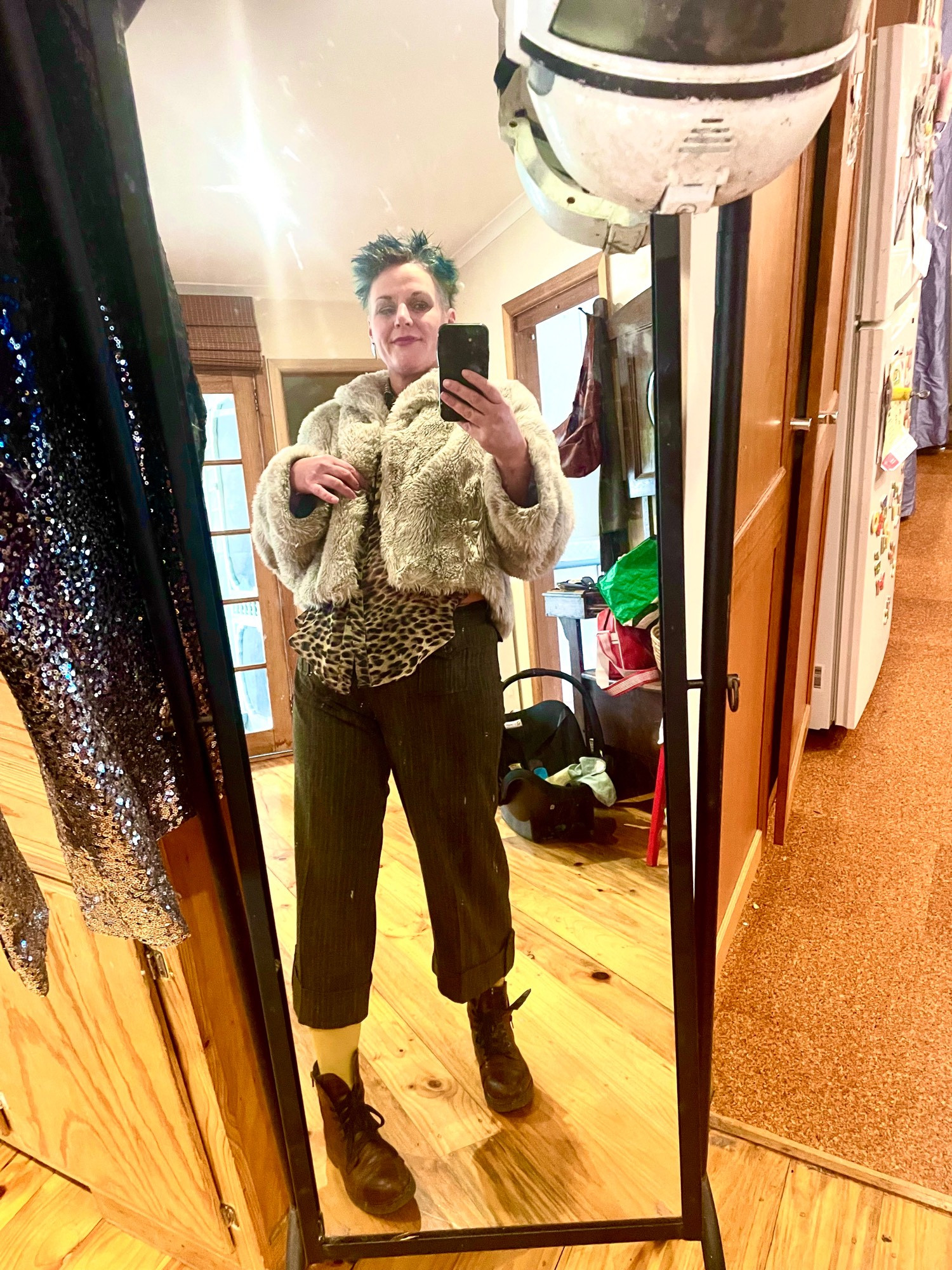 Spikey blue green hair
Mildly smug expression
Big grey fake fur jacket
Leapord skin translucent blouse 
Twill and quite tailored 3/4 pant
Yellow socks and chestnut lace up ankle boots