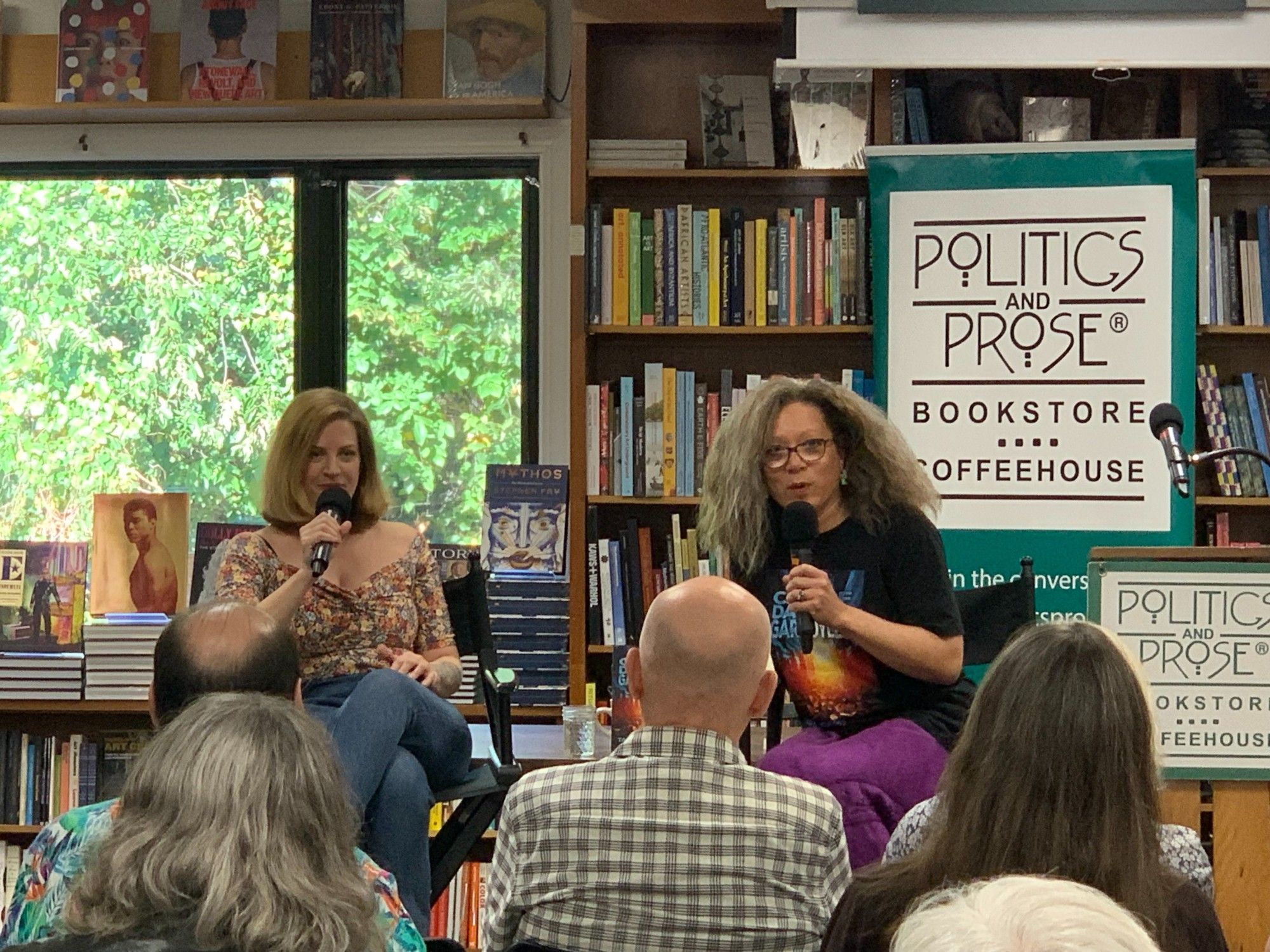 Amber Sparks interviewing Tara Campbell at Politics and Prose Bookstore. Both speakers sit in front of a wall of books and face the audience during the question and answer portion of the event.