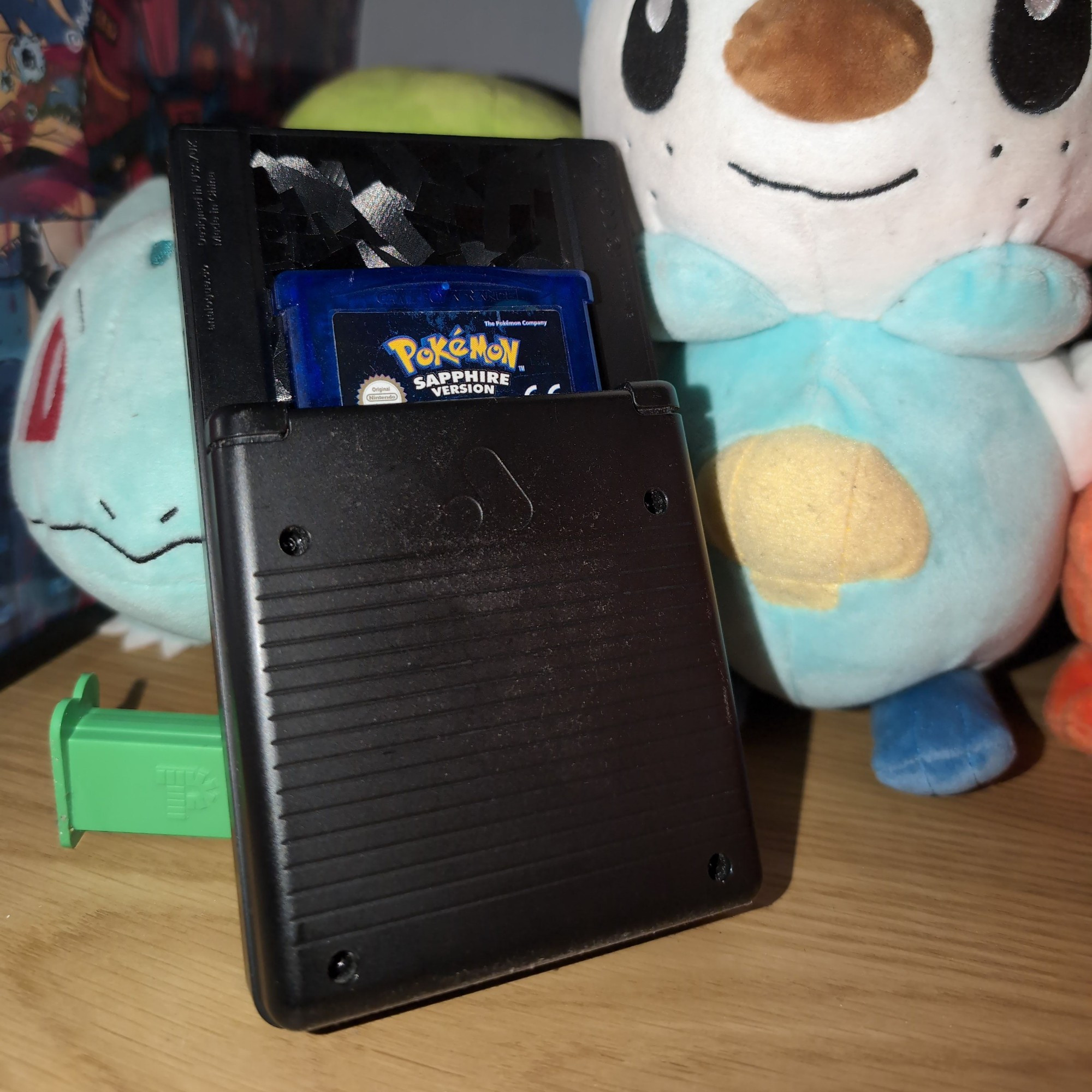 Analogue Pocket Back With Oshawott and Bulbasaur Plushies and the game Pokémon Sapphire