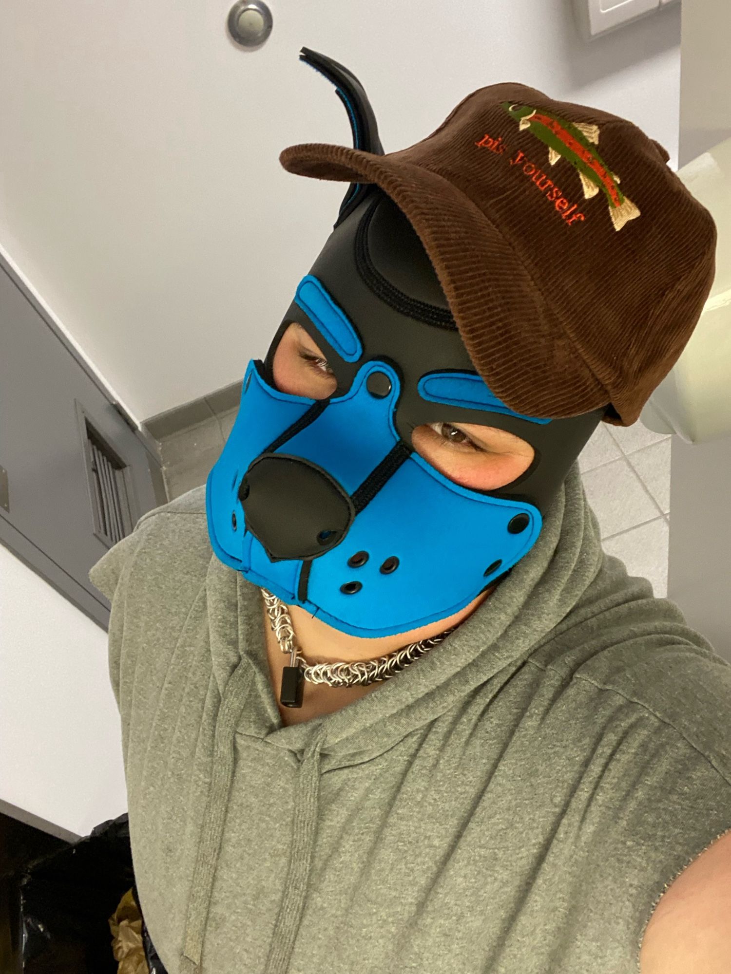 Selfie of me in pup hood wearing a brown hat with a fish on it that says: Piss yourself