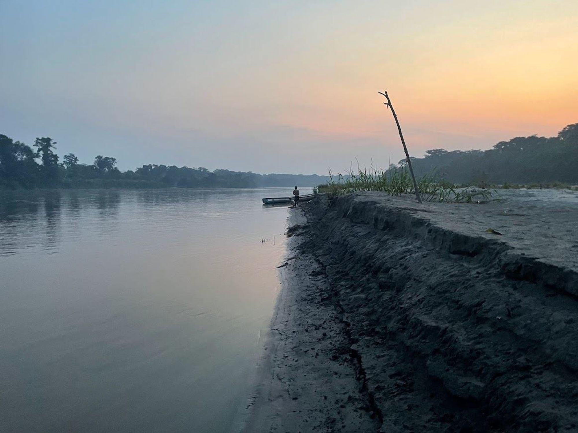 A lone figure on a river is seen at dawn.