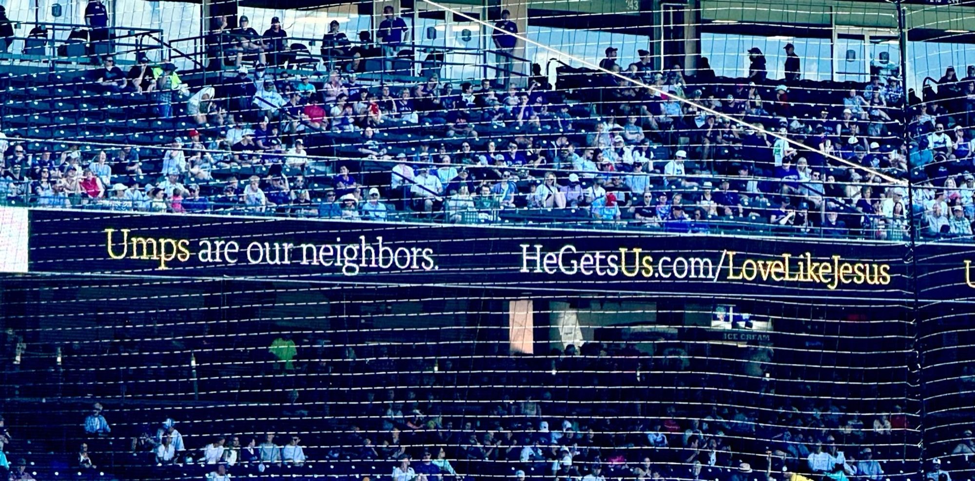 An advertisement at a baseball game: “Umps are our neighbors. HeGetsUs.com/LoveLikeJesus”