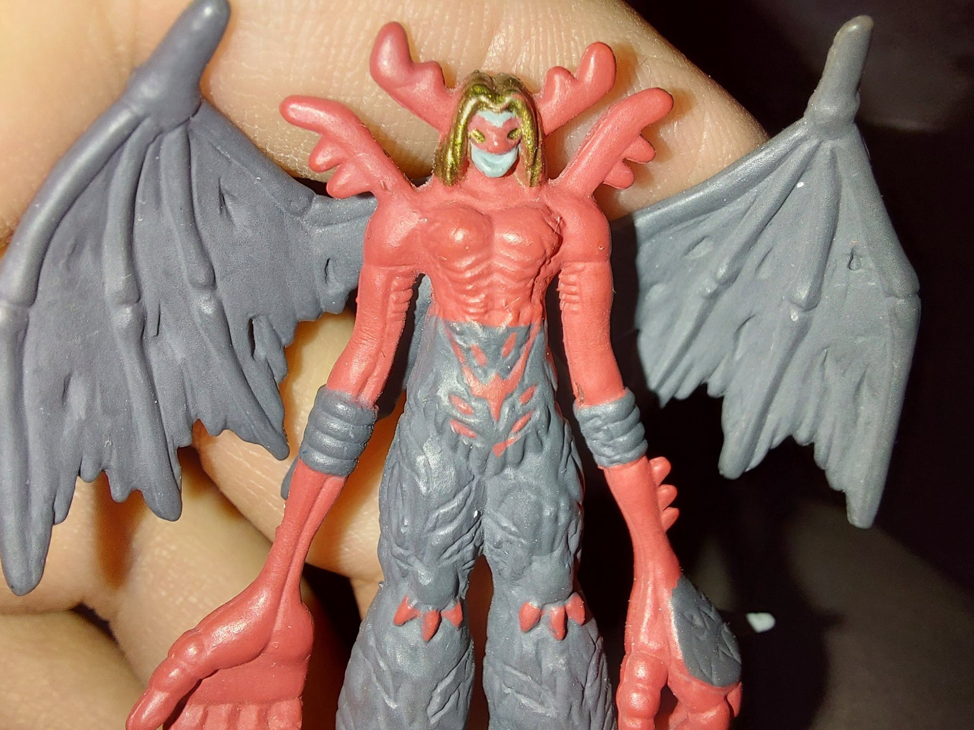 A close up photo of a ~1.5" digimon (VenomMyotismon) figure. My hand is in the background holding him up.