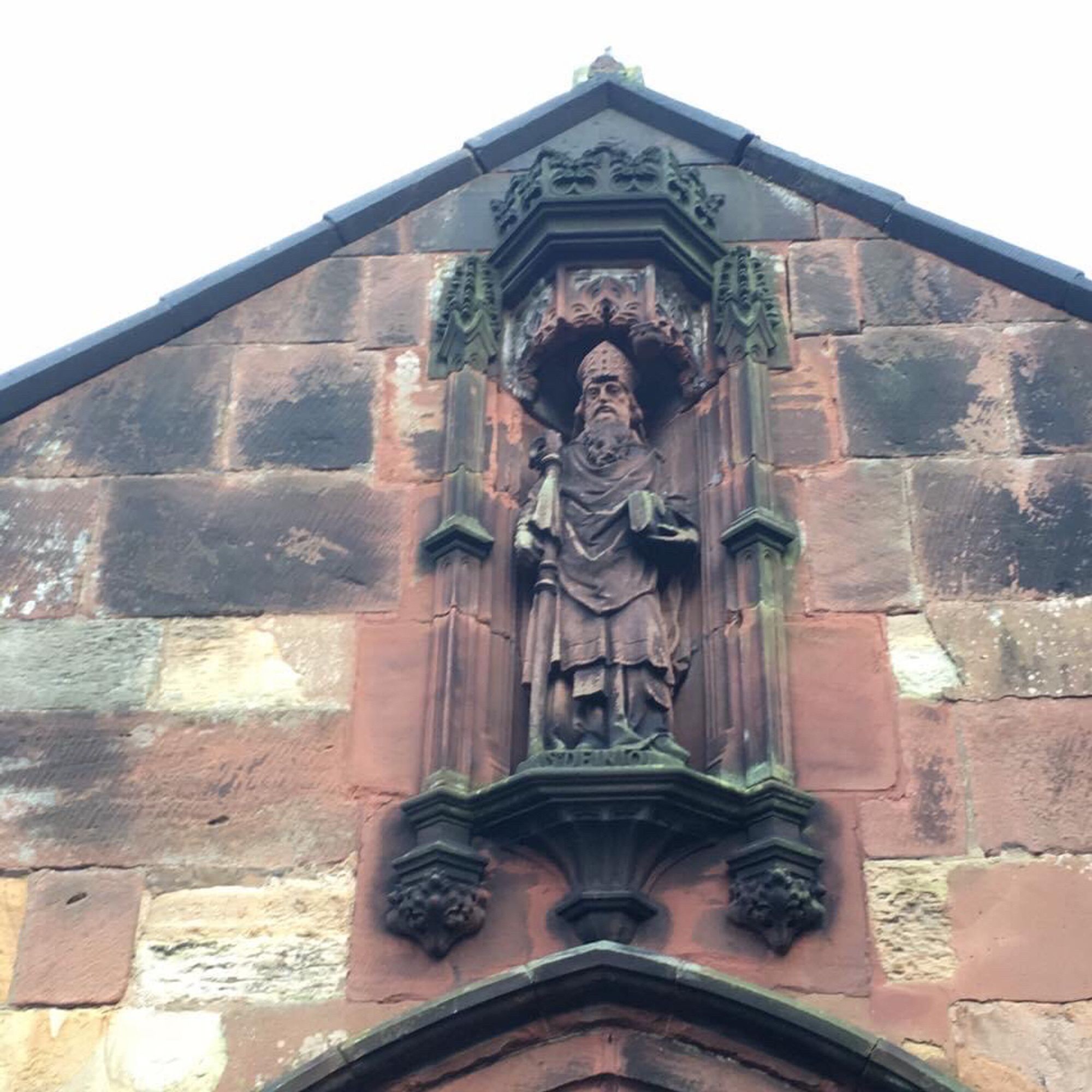 Statue of St Deiniol on his church in Hawarden.