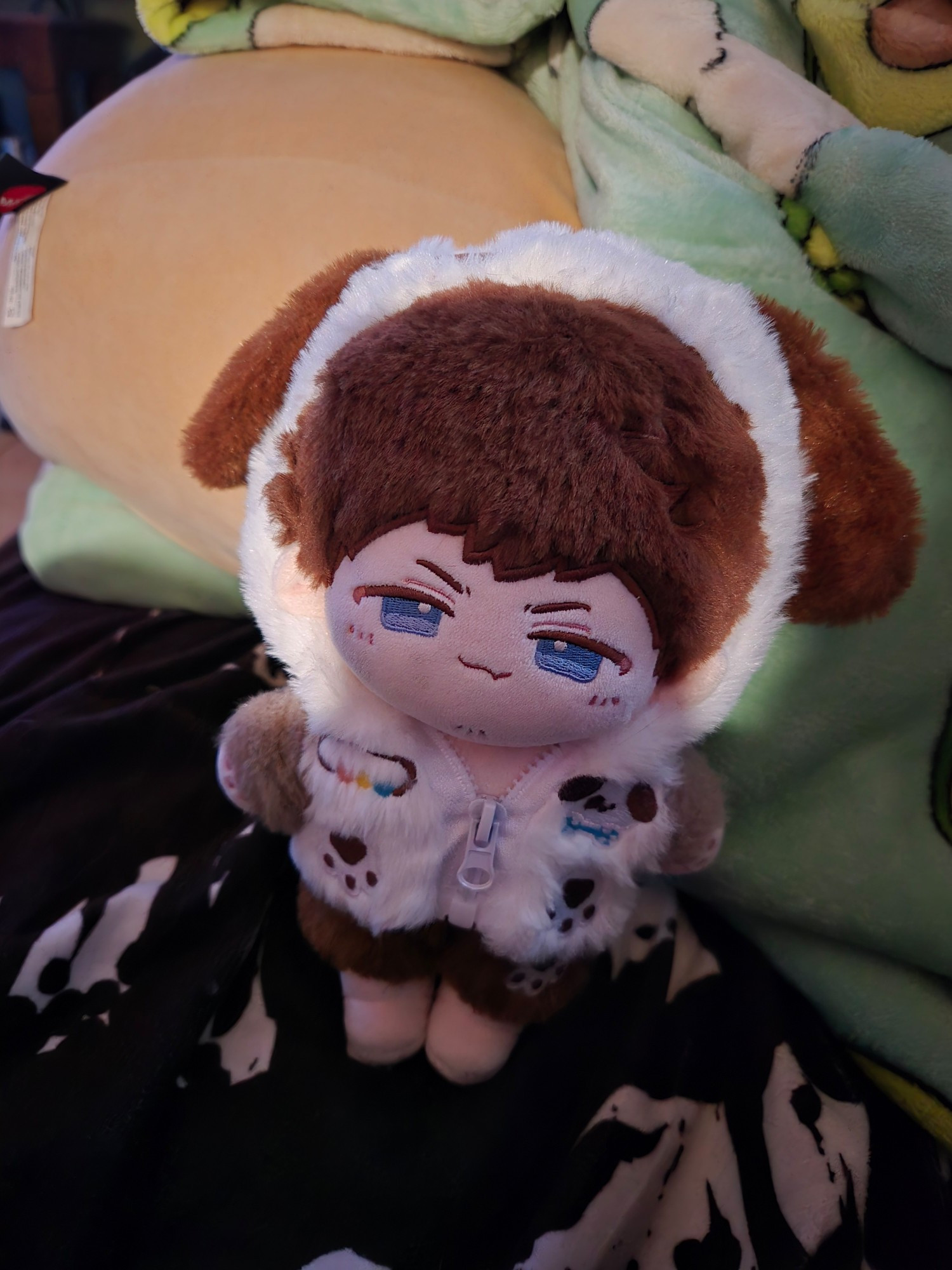 Doll of one Ardbert Hylfyst dressed in brown and white puppy pajamas(I have no respect for his dignity he is here for my entertainment) propped up against a baby Yoda squishmallow for no reason except that I'm too lazy to frame a shot properly.