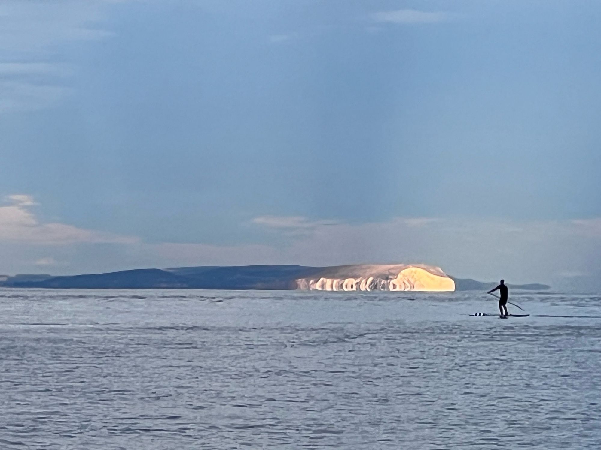 Paddle-boarder on the sea with the white cliffs (the ‘needles’) of the Isle of Wight behind them