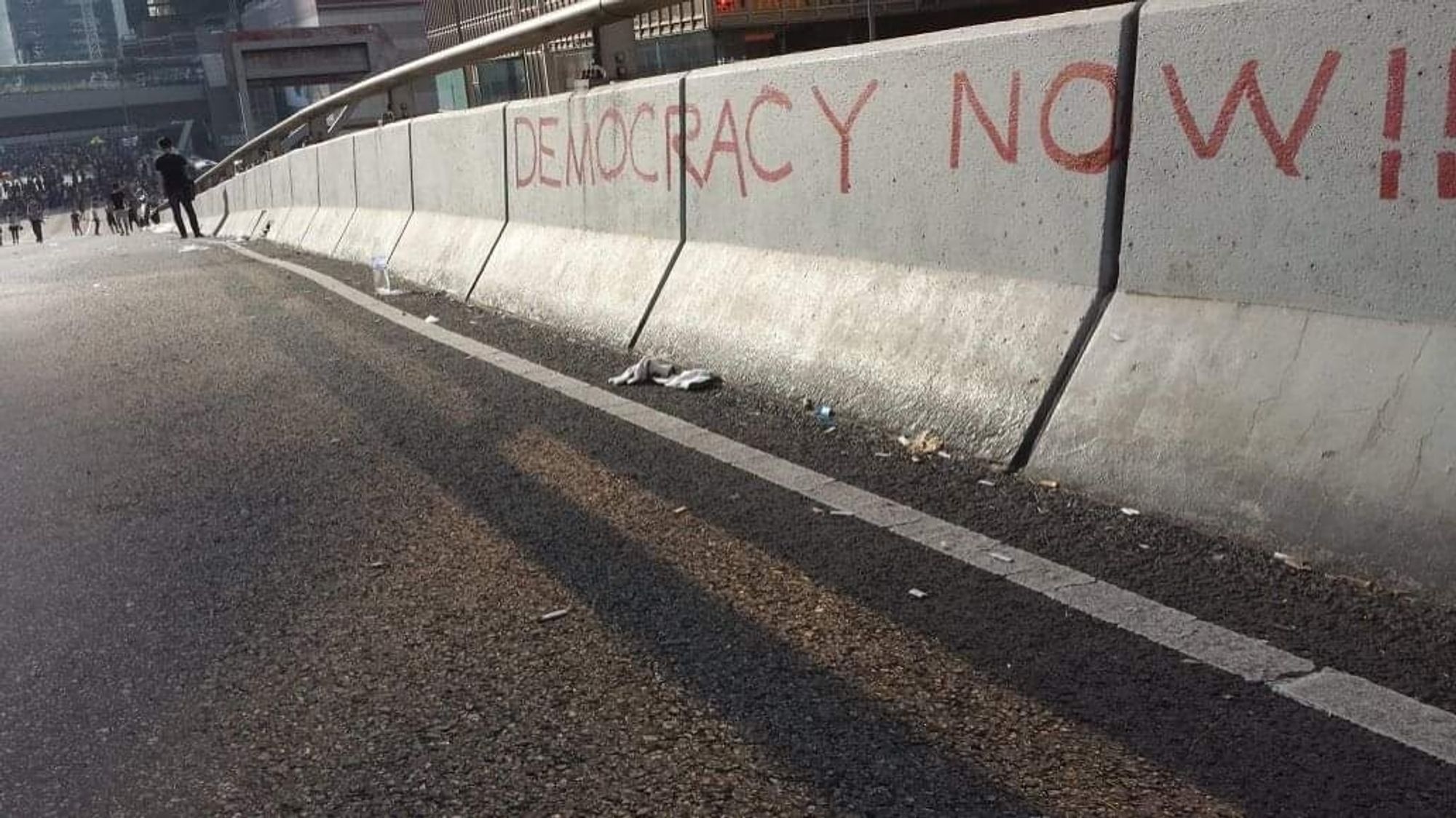 The words "democracy now" written on a concrete road divider in Hong Kong's Harcourt Road.