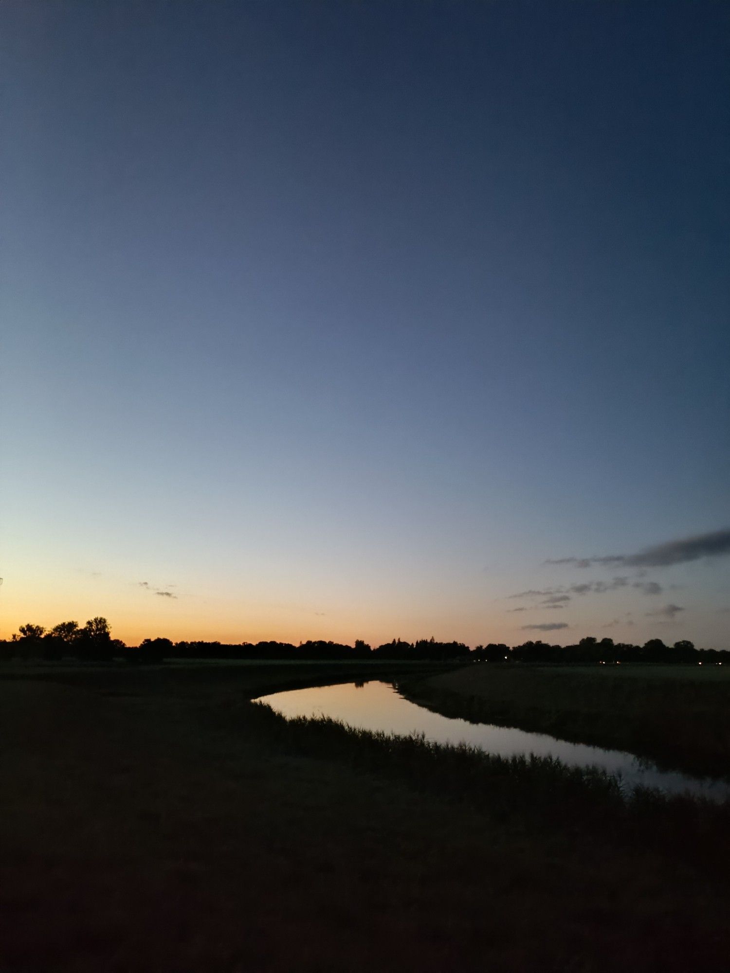 Biegung Jeetzelkanal, Himmel dunkelblau, Horizont mit diesem besonderen Abendleuchten ins Orange, dass sich im Fluss spiegelt.