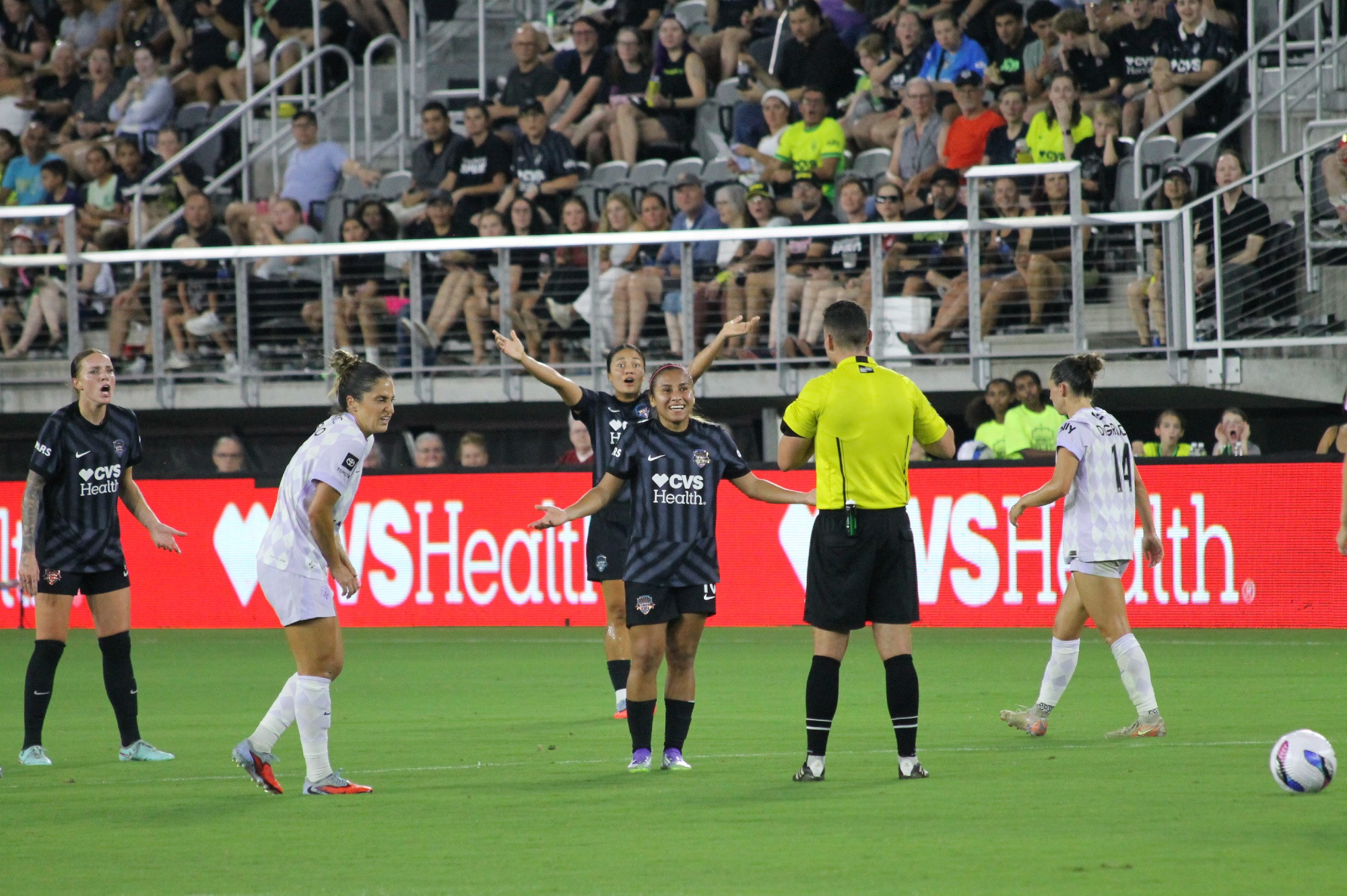 Leicy Santos smiles with her arms spread out toward the referee as Rebeca Bernal has her arms up and has a shocked look on her face. At the far left, Hal Hershfelt looks quite upset and in between them, Savannah DeMelo of Racing Louisville has a pained expression