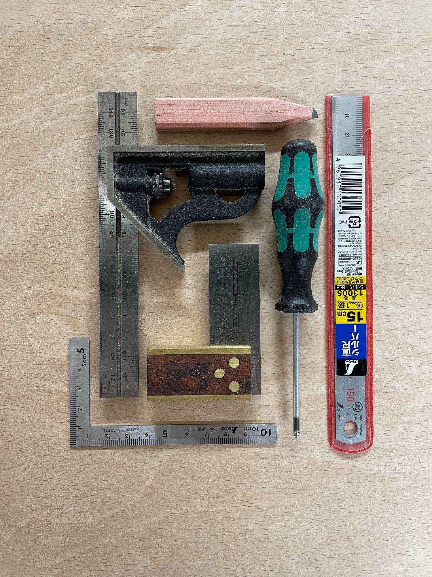 A selection of small scale tools including a combi square, a 150mm ruler and a used pencil