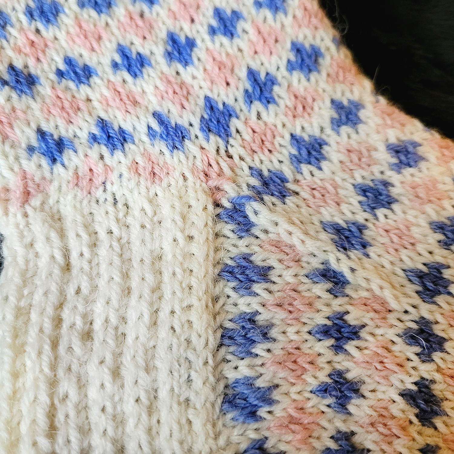 A detail of the socks. A pattern of pink and blue fleur de lis extends through the sock, with the exception of the heel being white.