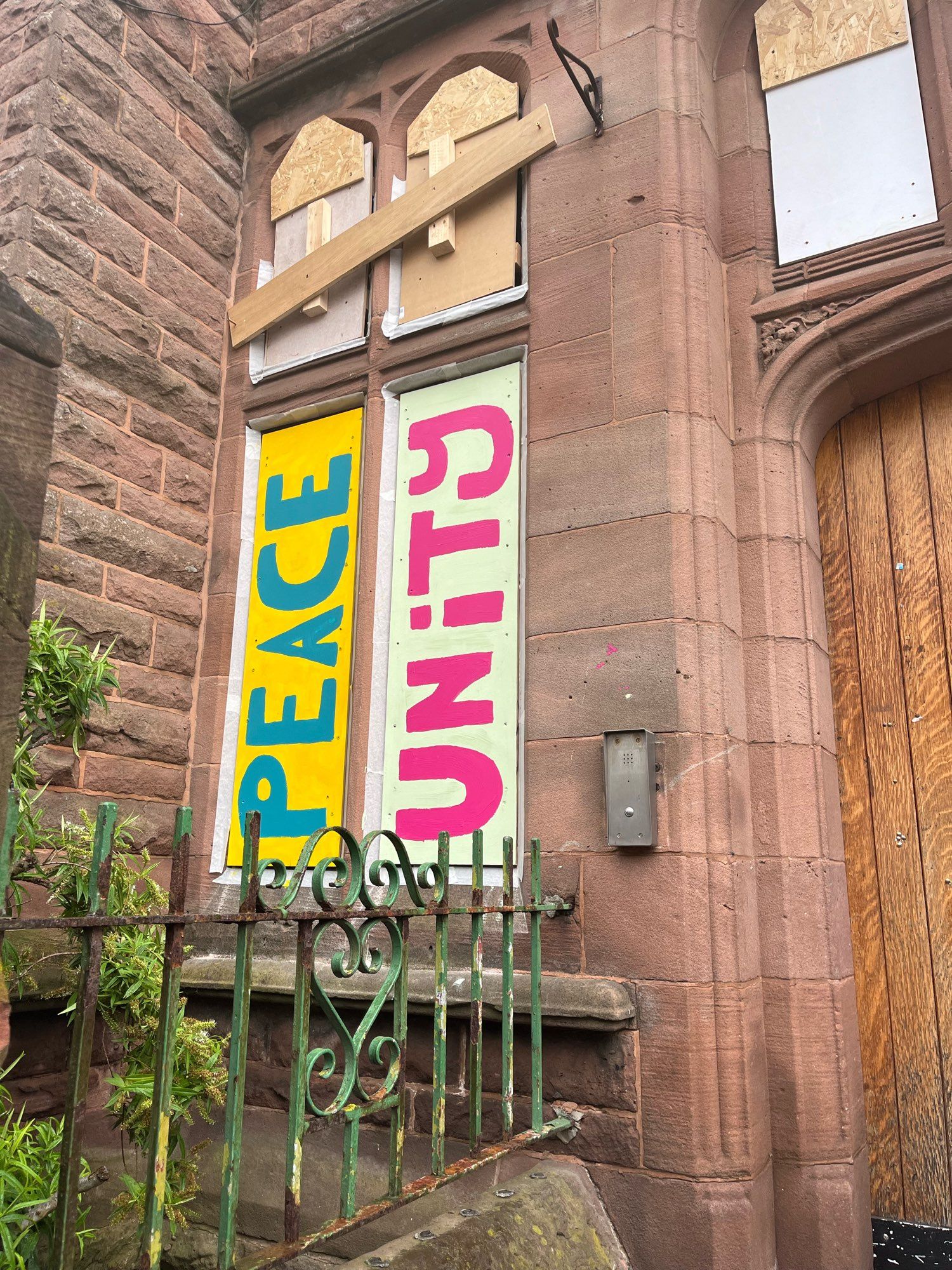 More words painted on boarded windows - peace and unity. Blue on yellow & Red on green.