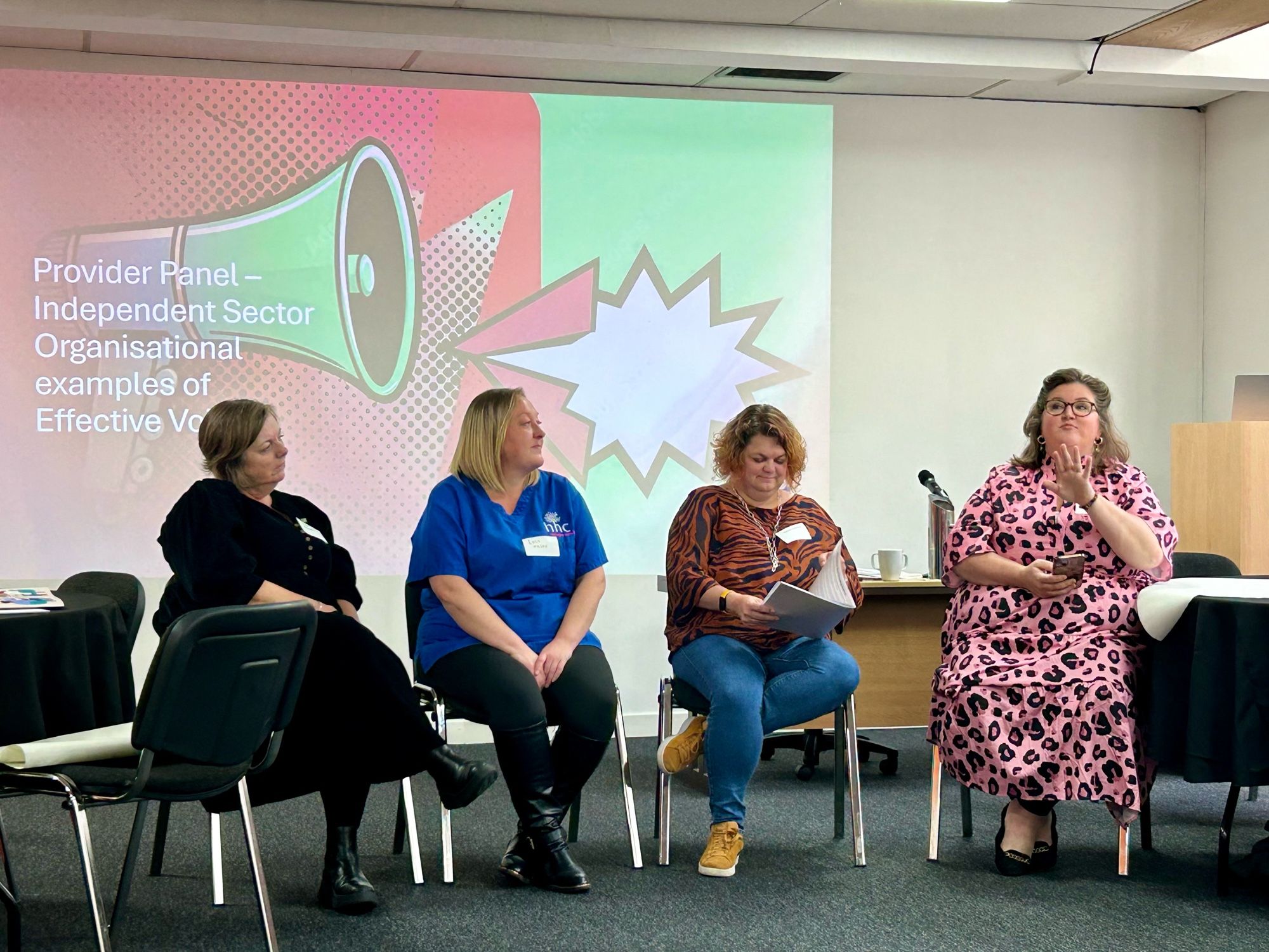 4 female panelists in front of projection of loud speaker