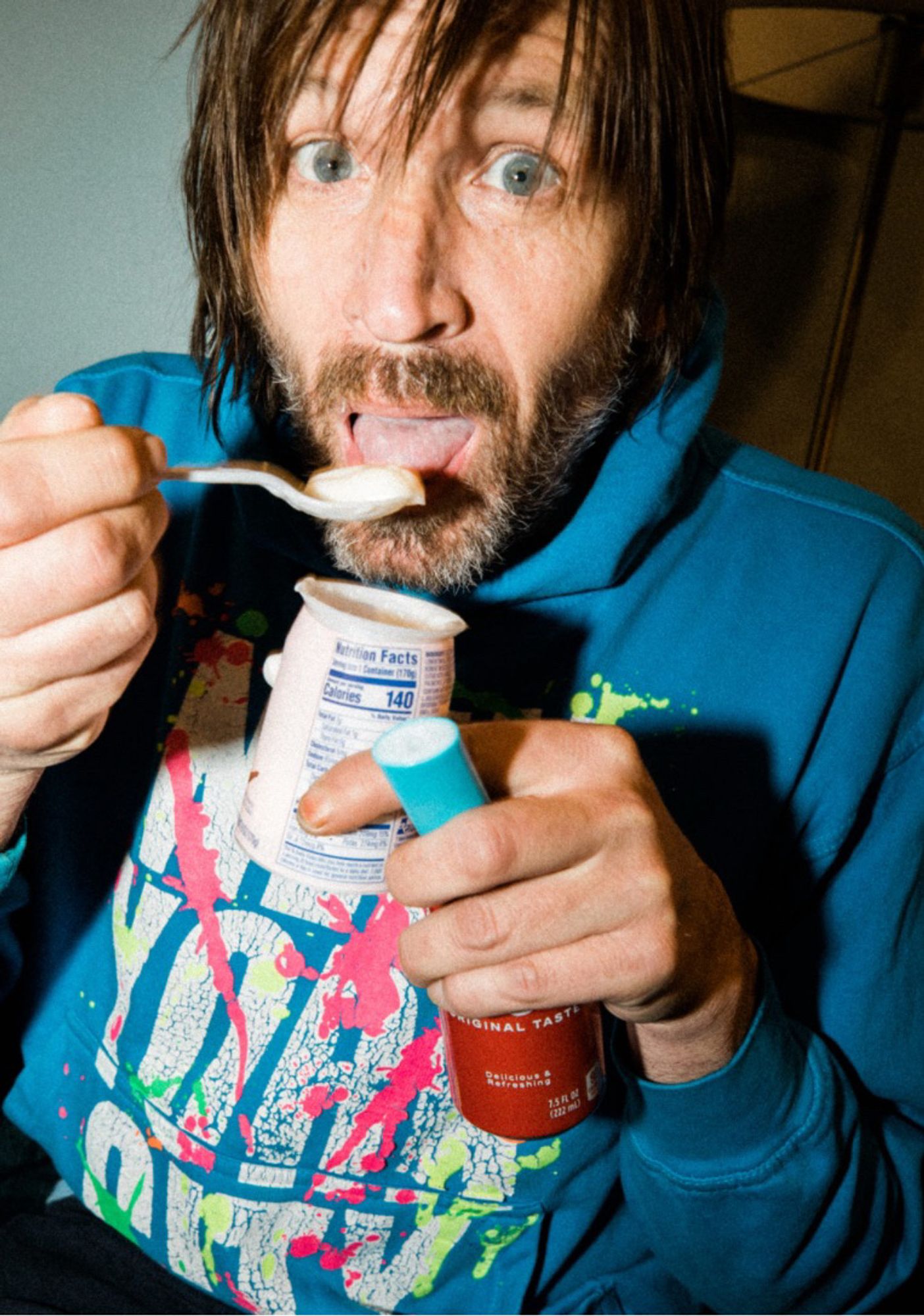 A bearded Evan Dando, eating yogurt circa 2022 in a teal hoodie