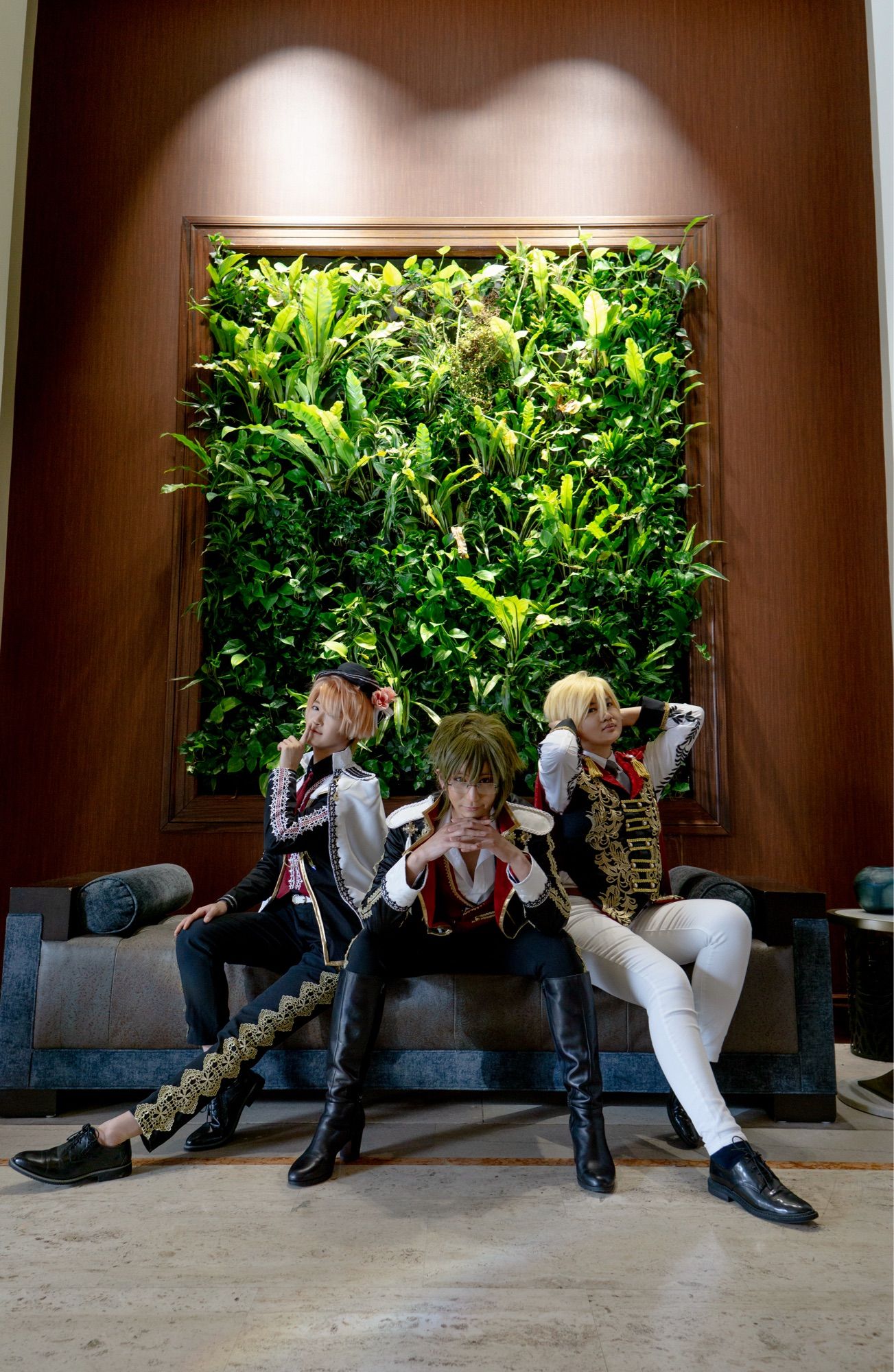 cosplay photo: mitsuki, yamato, nagi sitting on a dark blue couch against a wall decorated with plants