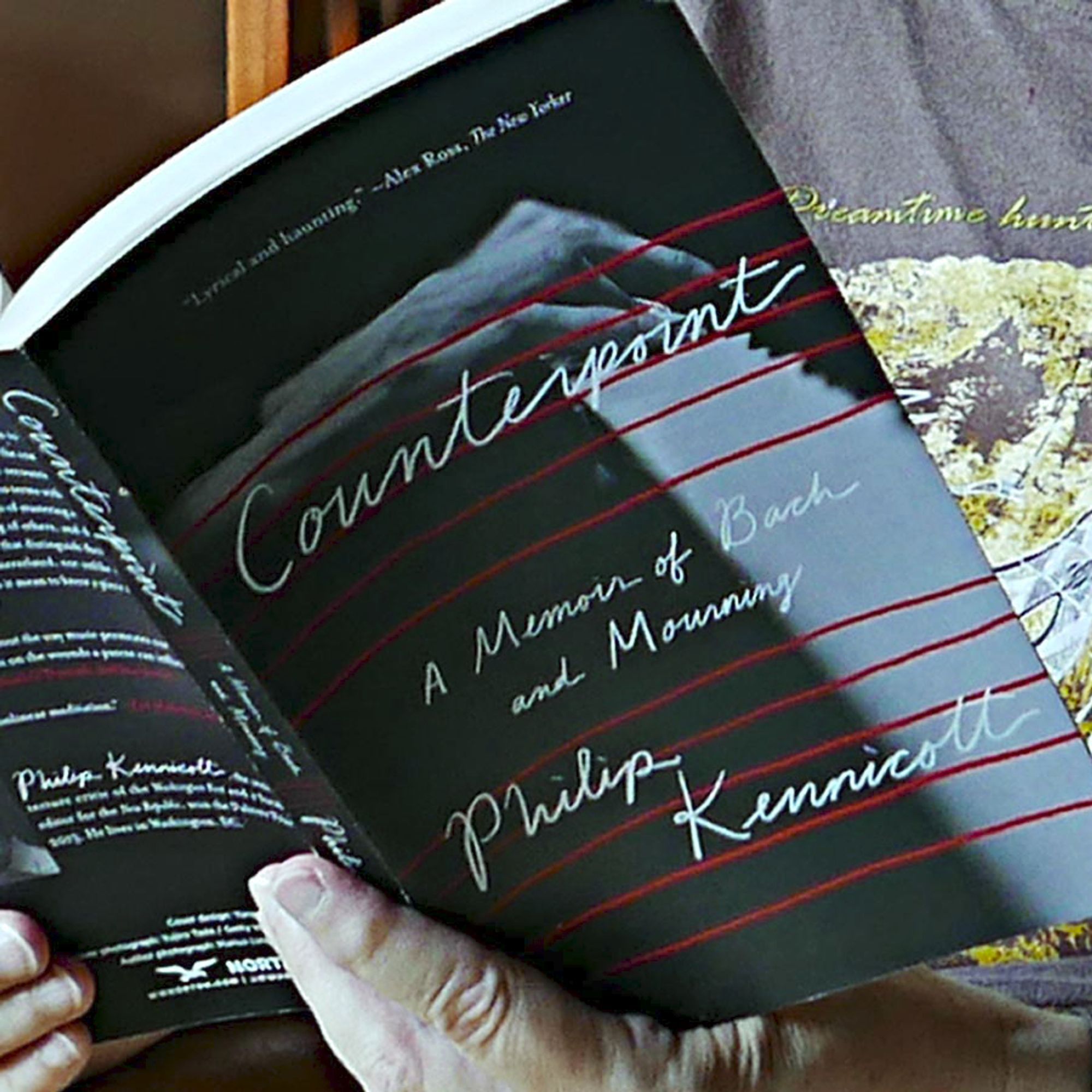 Close up of paperback cover of Philip Kennicott's Counterpoint: A Memoir of Bach and Mourning, book held open by hands.