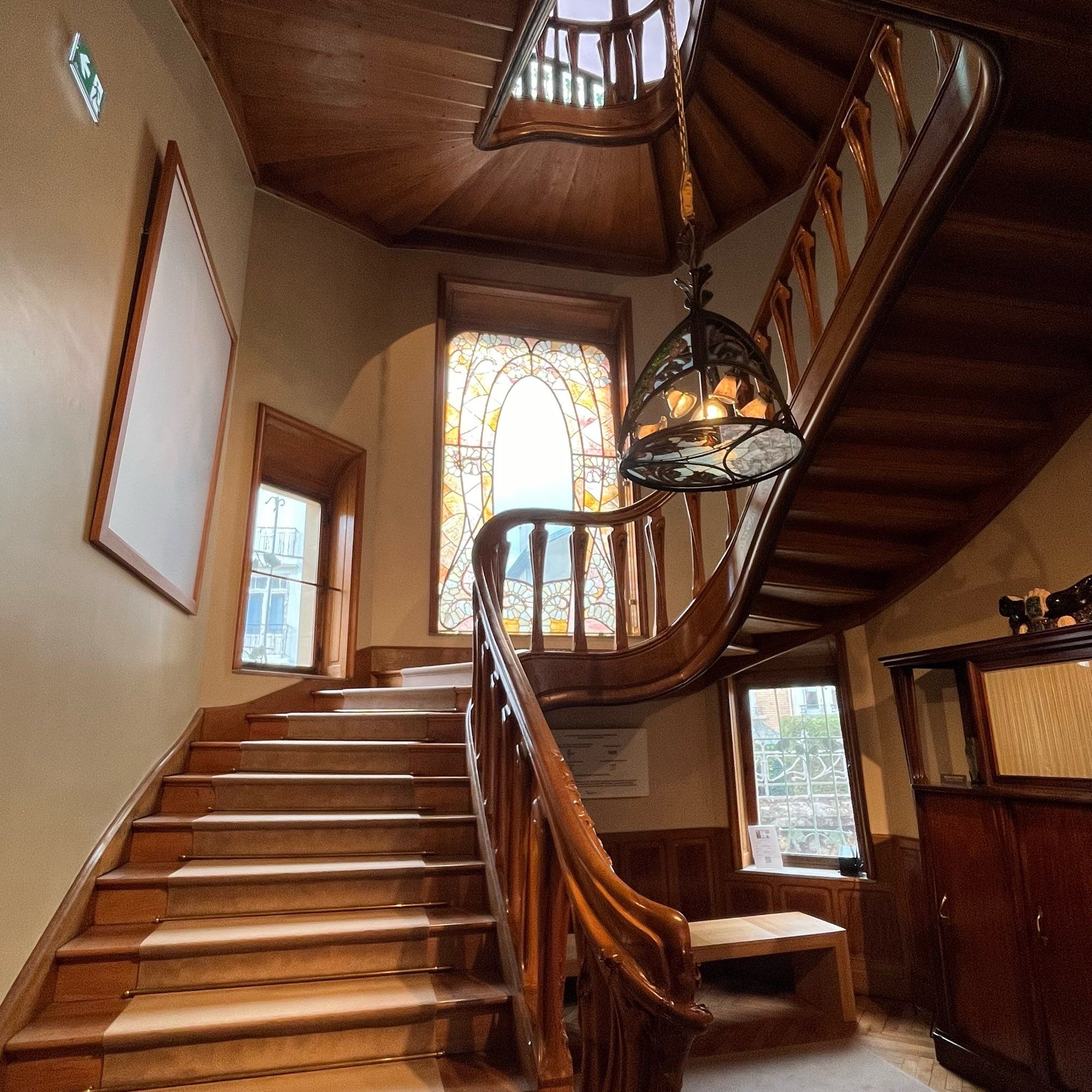 The curving wooden staircase of the Villa Majorelle, with an ornate glass hanging lamp