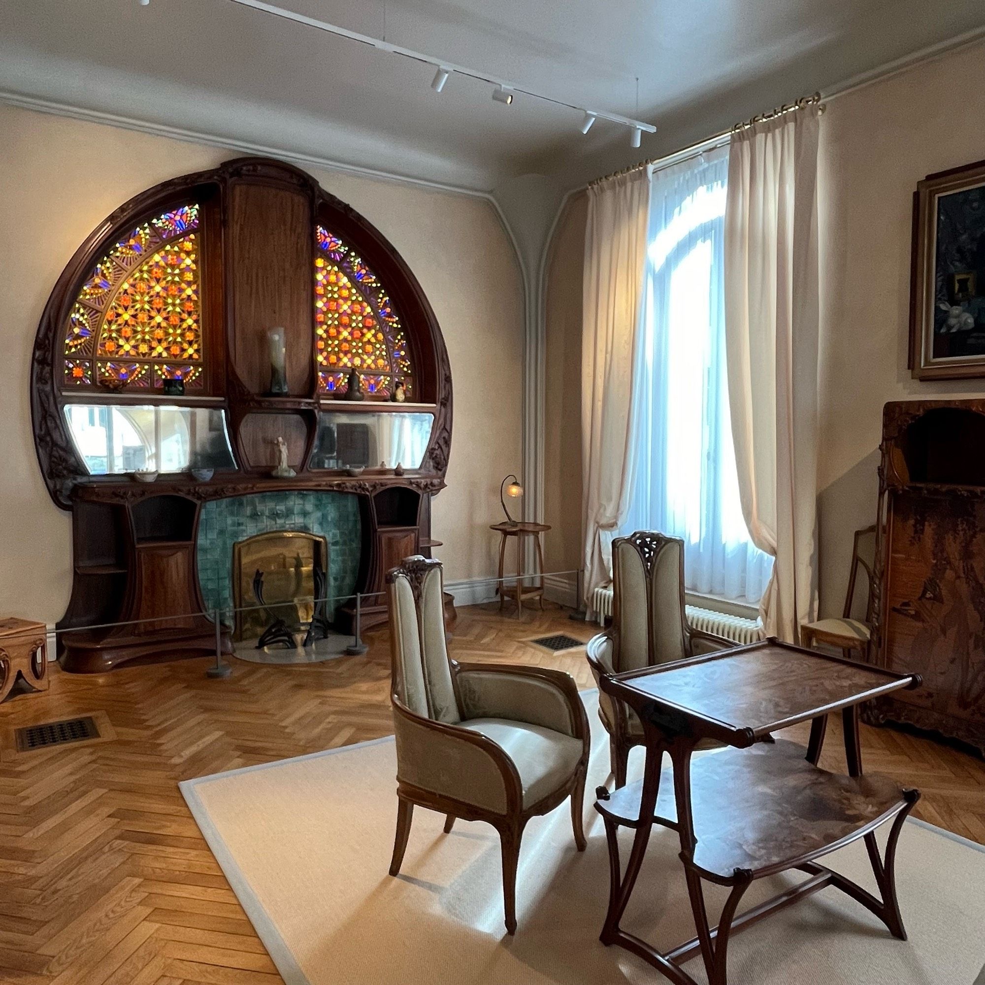 The living room of the Villa Majorelle, which has a curving fireplace incorporating two stained glass window panels