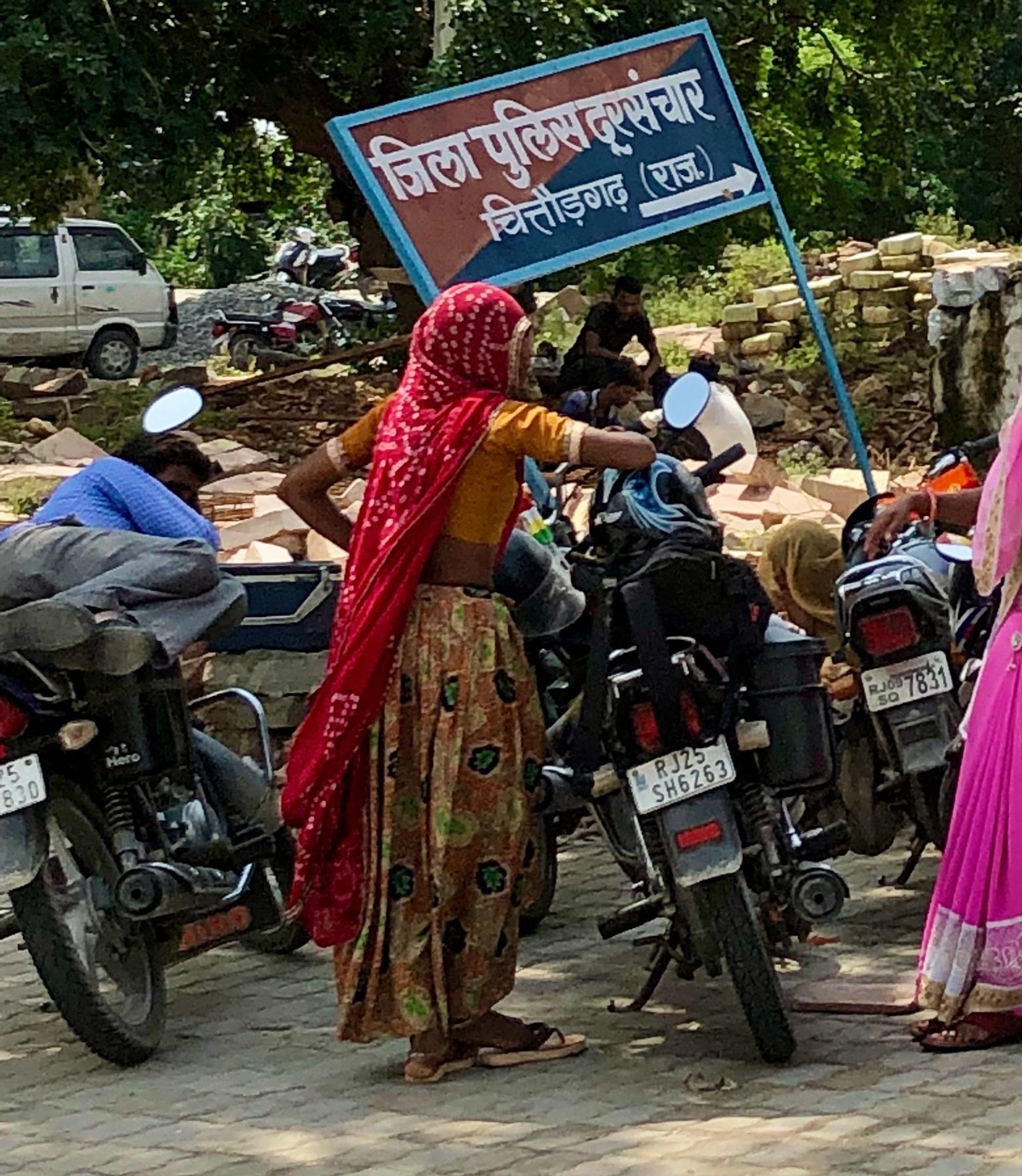 Femme en sari rouge et pantalon ocre s’apprêtant à monter sur une moto