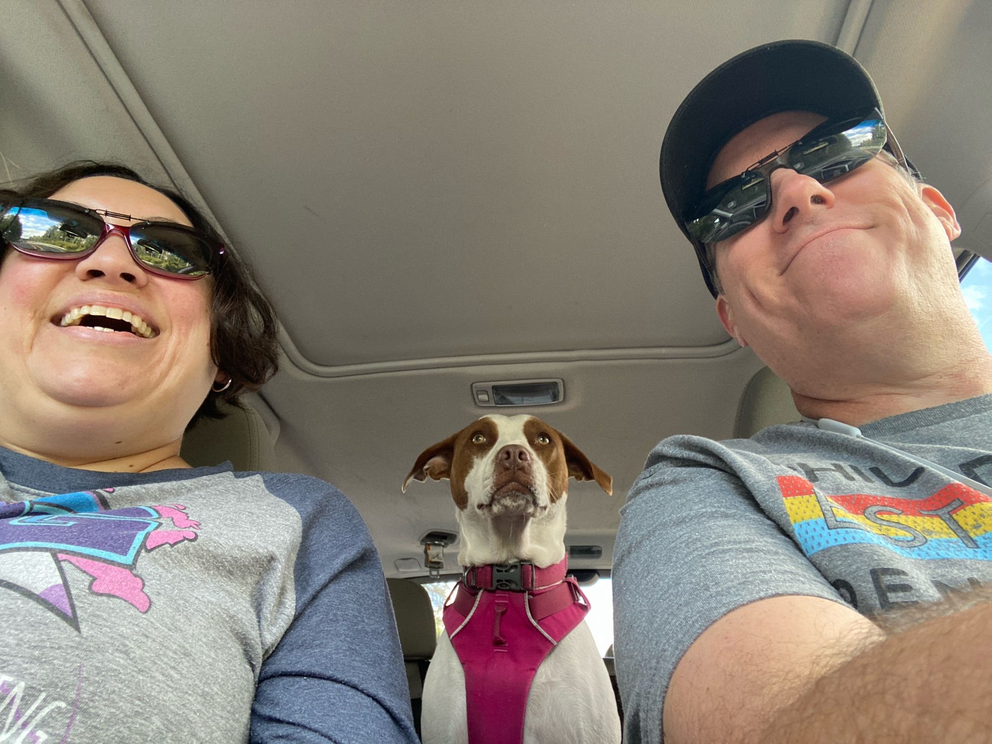 Car photo with two smiling people and a stoic dog in the backseat