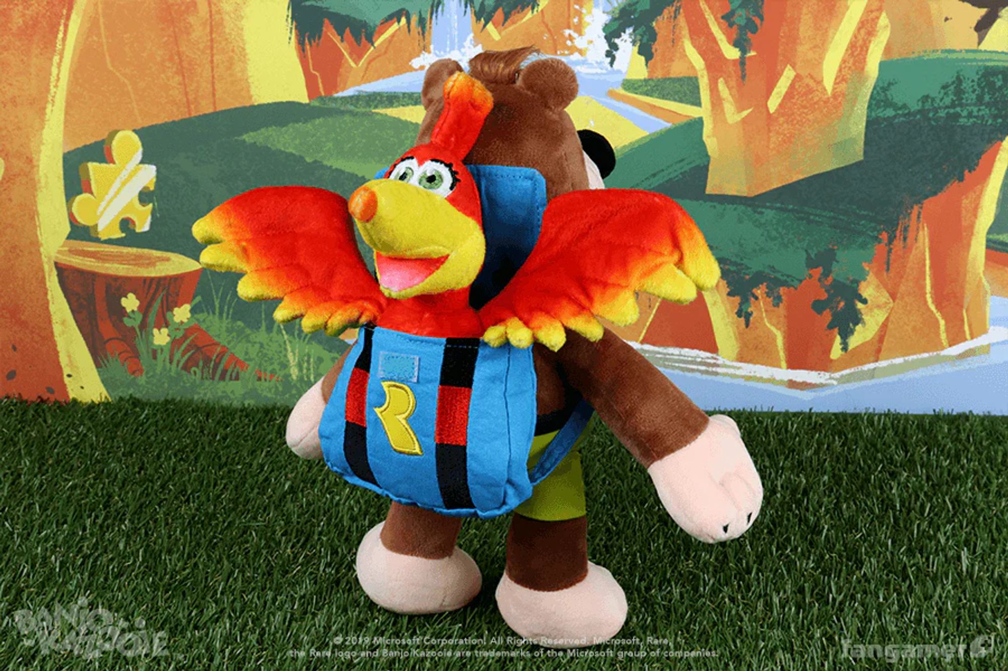 A plush Banjo facing backwards to show the removable Kazooie plush in its backpack, photographed in front of a Banjo-Kazooie scene.