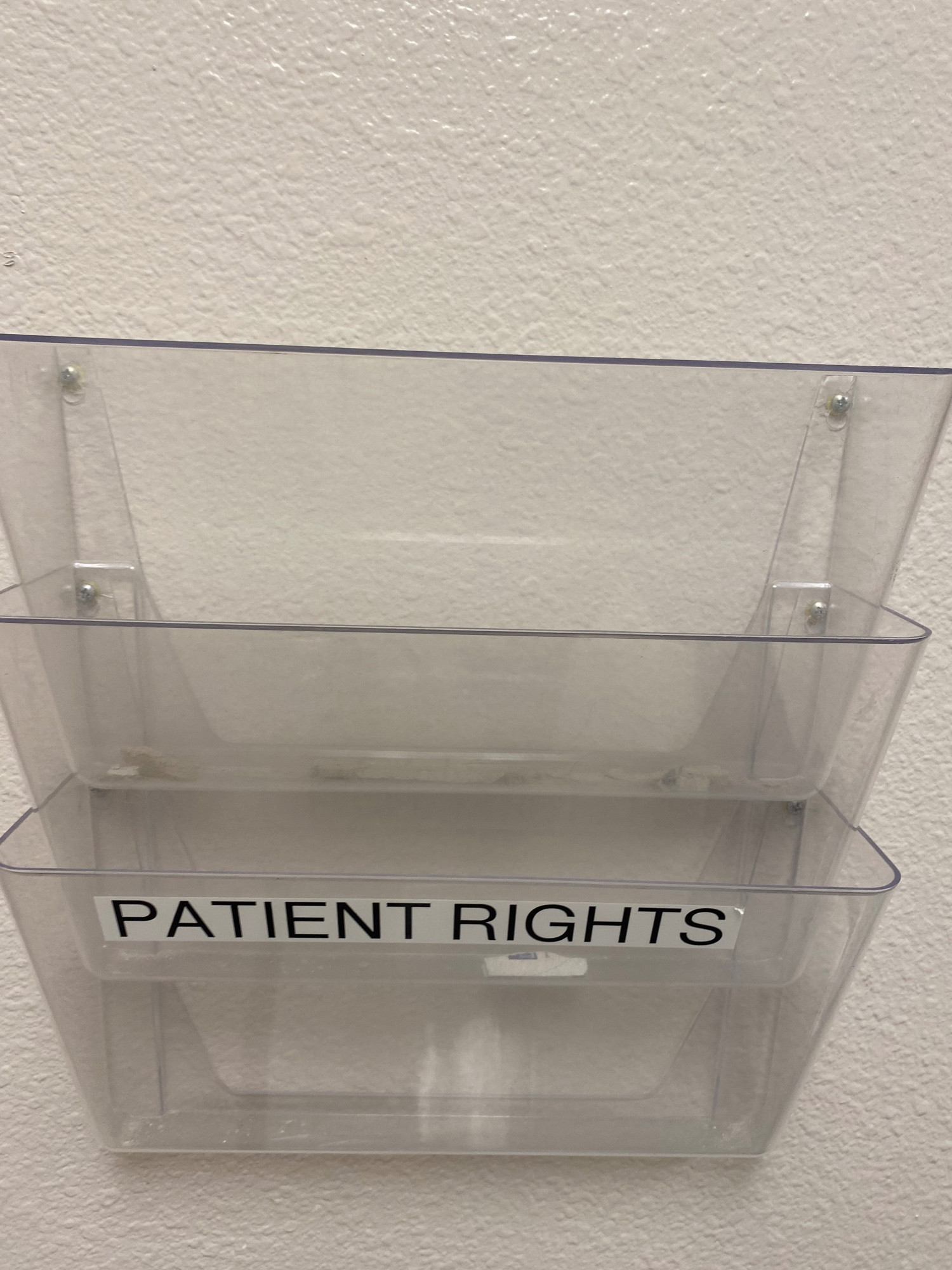 A set of folders attached to a wall and labeled "patient rights". They are empty