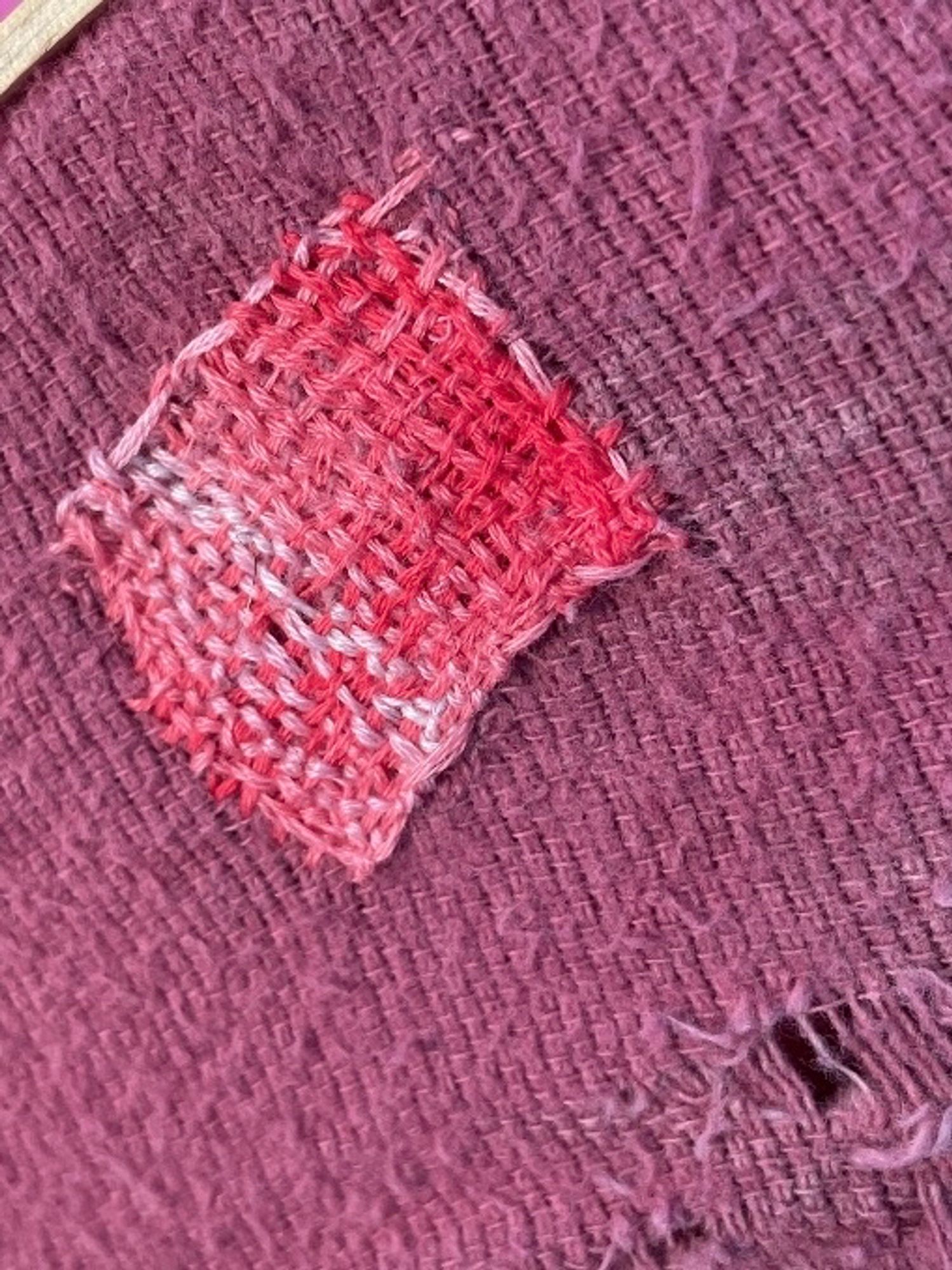 Darned patch on rose colored blanket with stitching in varigated pinks. Pic 2 is a close-up of very sloppy stitching. 
A woobie is a cross between a blanket and a poncho and a shawl, depending on how you wear it.