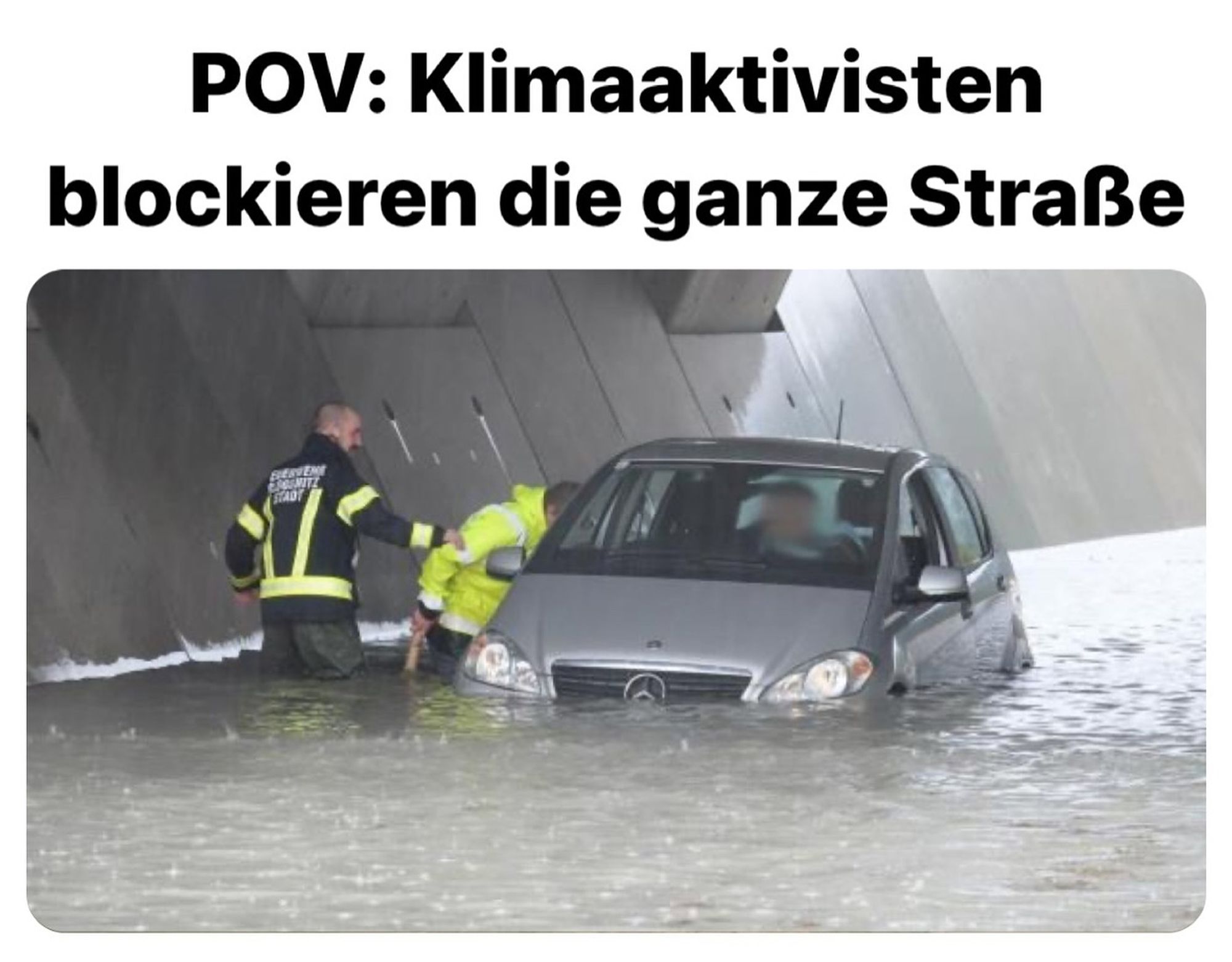 Ein Auto das zur Hälfte in einer Unterführung im Wasser steht. Männer in gelben Warnwesten versuchen die Personen im Auto zu befreien. Dazu der Text: klimaaktivisten blockieren die ganze Straße