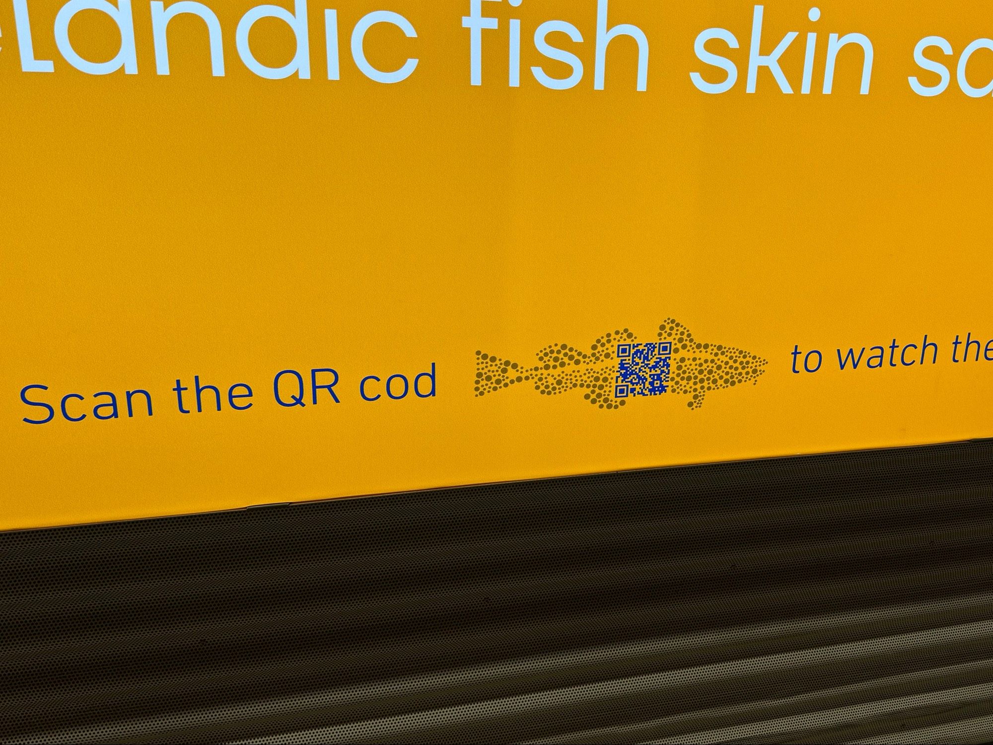 a photograph of an ad that says "scan the qr cod" and has a illustration of a pixellated cod, with a qr code in the middle of it.