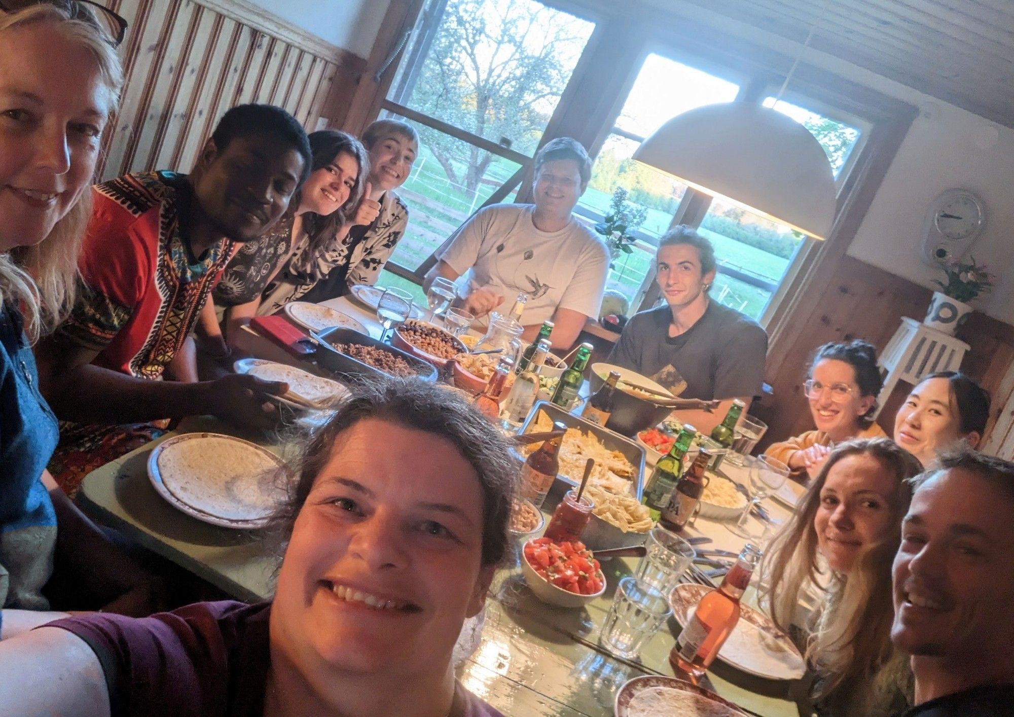 Students and researchers from the 2024 flycatcher monitoring field season sit around a table for dinner .