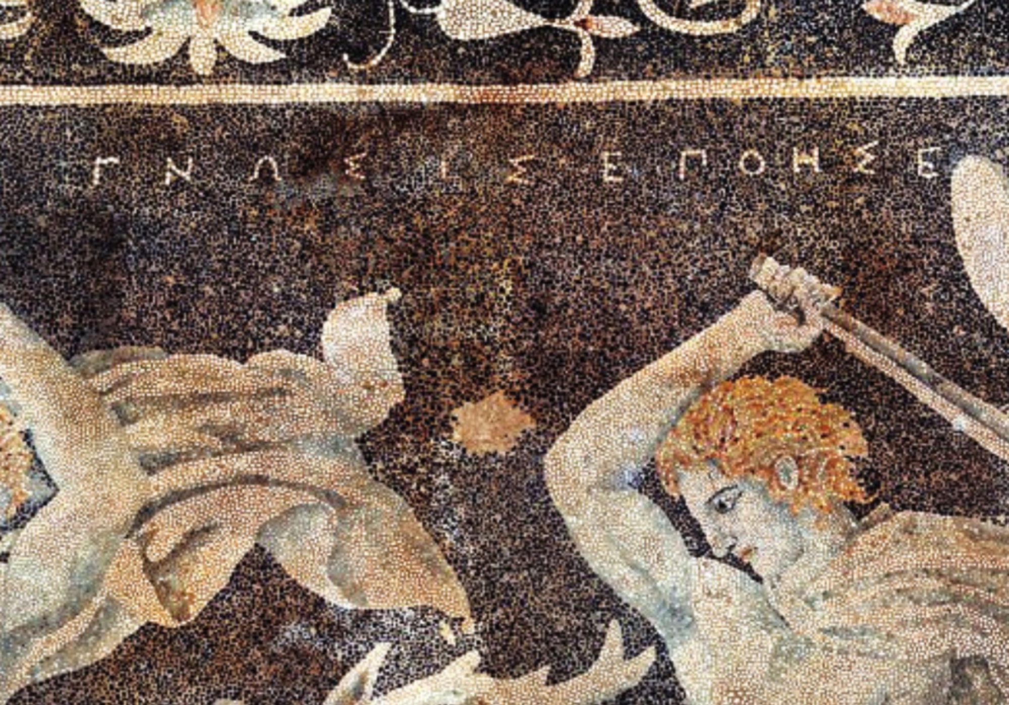 Mosaic signature detail: Stag hunt mosaic, Pella, Greece.
Français : Mosaïque de la chasse au cerf, Pella, Grèce.
The figure on the right is possibly Alexander the Great due to the date of the mosaic along with the depicted upsweep of his centrally-parted hair (anastole); the figure on the left wielding a double-edged axe (associated with Hephaistos) is perhaps Hephaestion, one of Alexander's loyal companions. For further infromation, see Chugg, Andrew (2006). Alexander's Lovers. Raleigh, N.C.: Lulu. ISBN 978-1-4116-9960-1, pp 78-79.