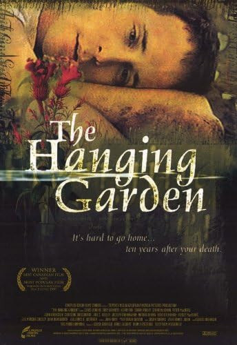 The Hanging Garden movie poster. The top third is a close up of main character Sweet William's face laying on his side on the ground staring at a flower. The middle has the movie's name and the bottom third is the movie tagline 'It's hard to go home...ten years after your death' and the movie's credits.