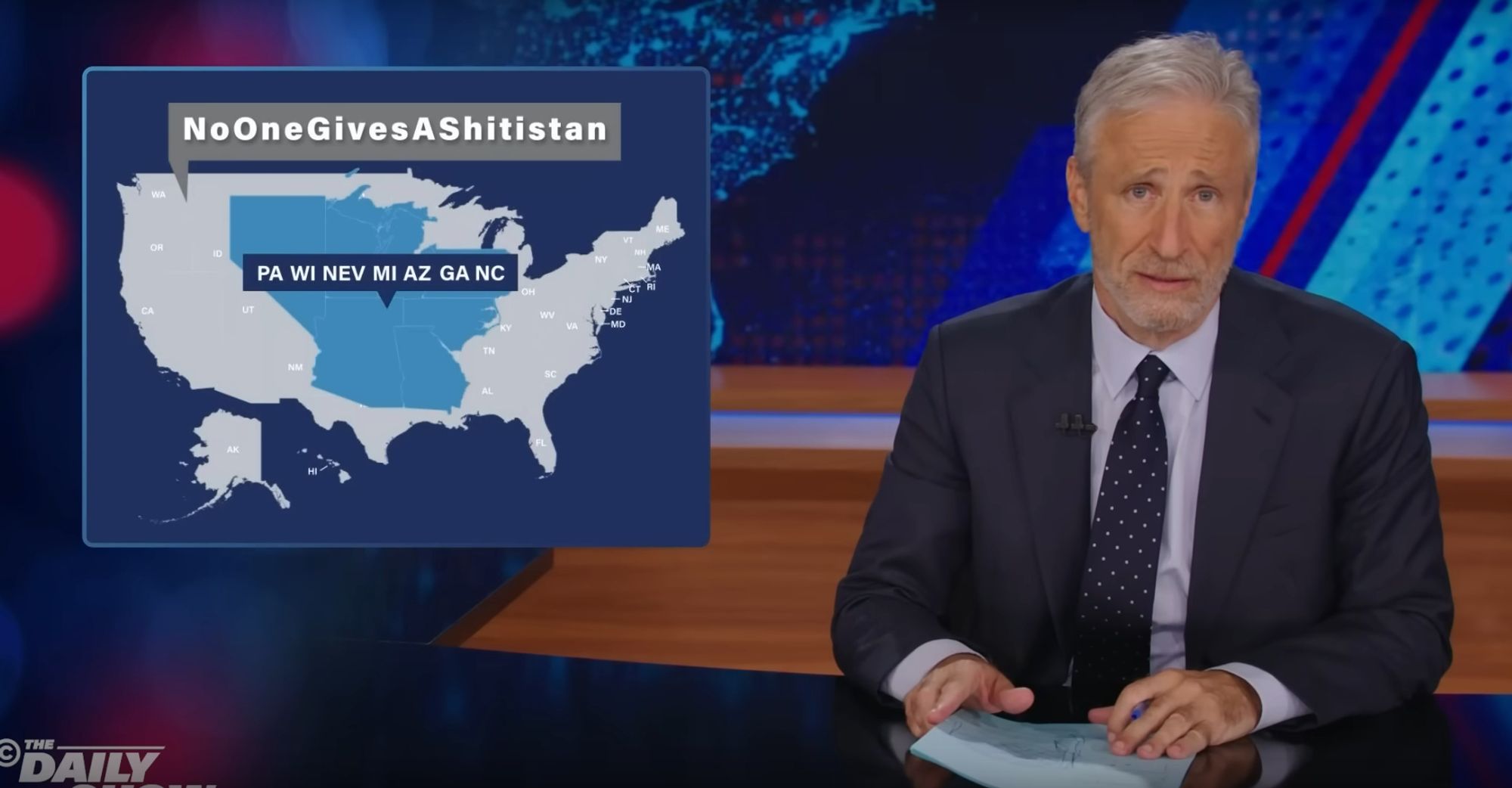 Comedian Jon Stewart appears on screen with a graphic showing two nations: the nation of "PA WI NEV MI AZ GA NC", that actually decides the election, and the nation of "No One Gives A Shit-istan," where the rest of us live but decide nothing.