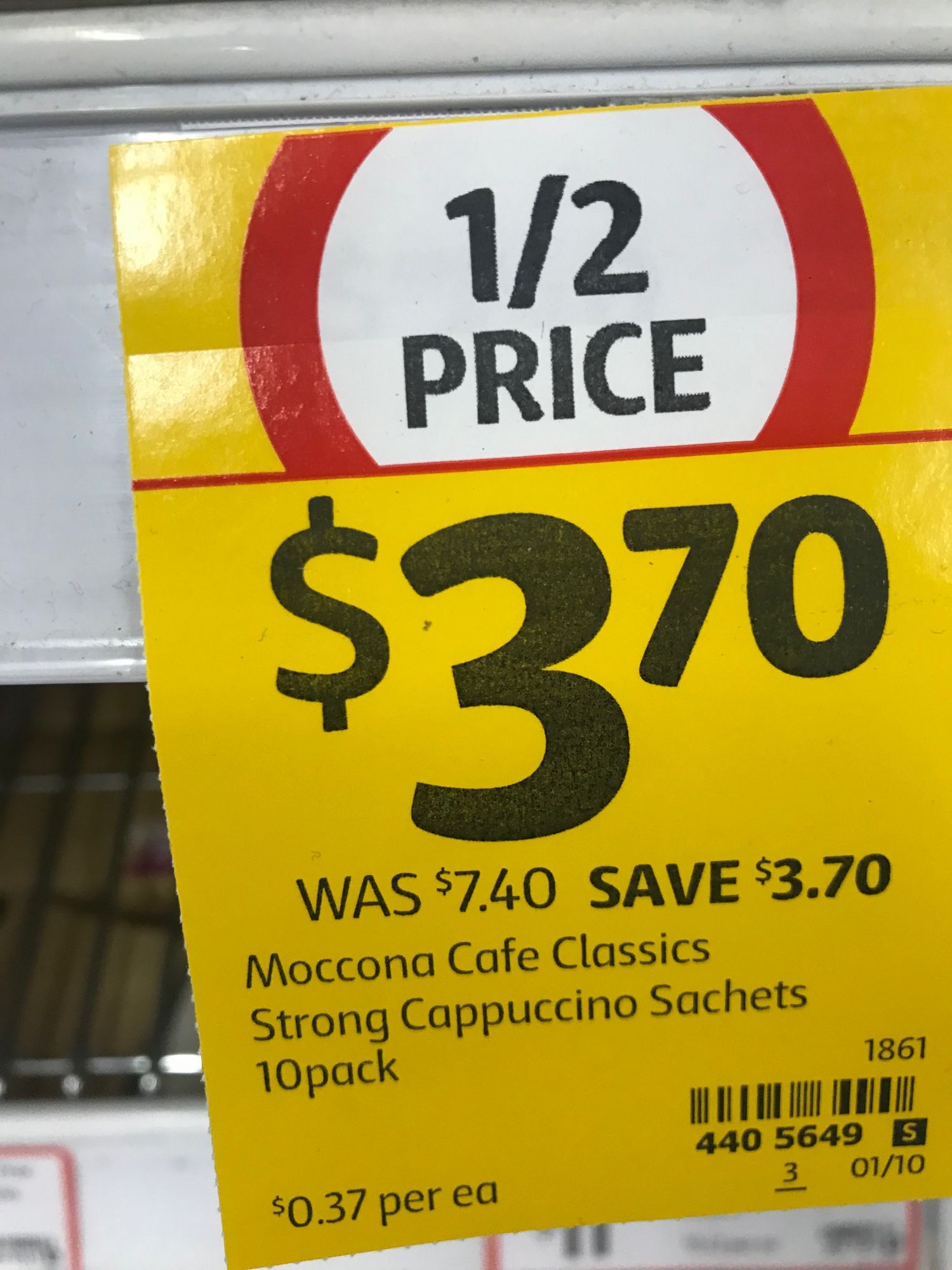 “1/2 Price” signage for Moccona coffee sachets saying “WAS $7.40 SAVE $3.70”