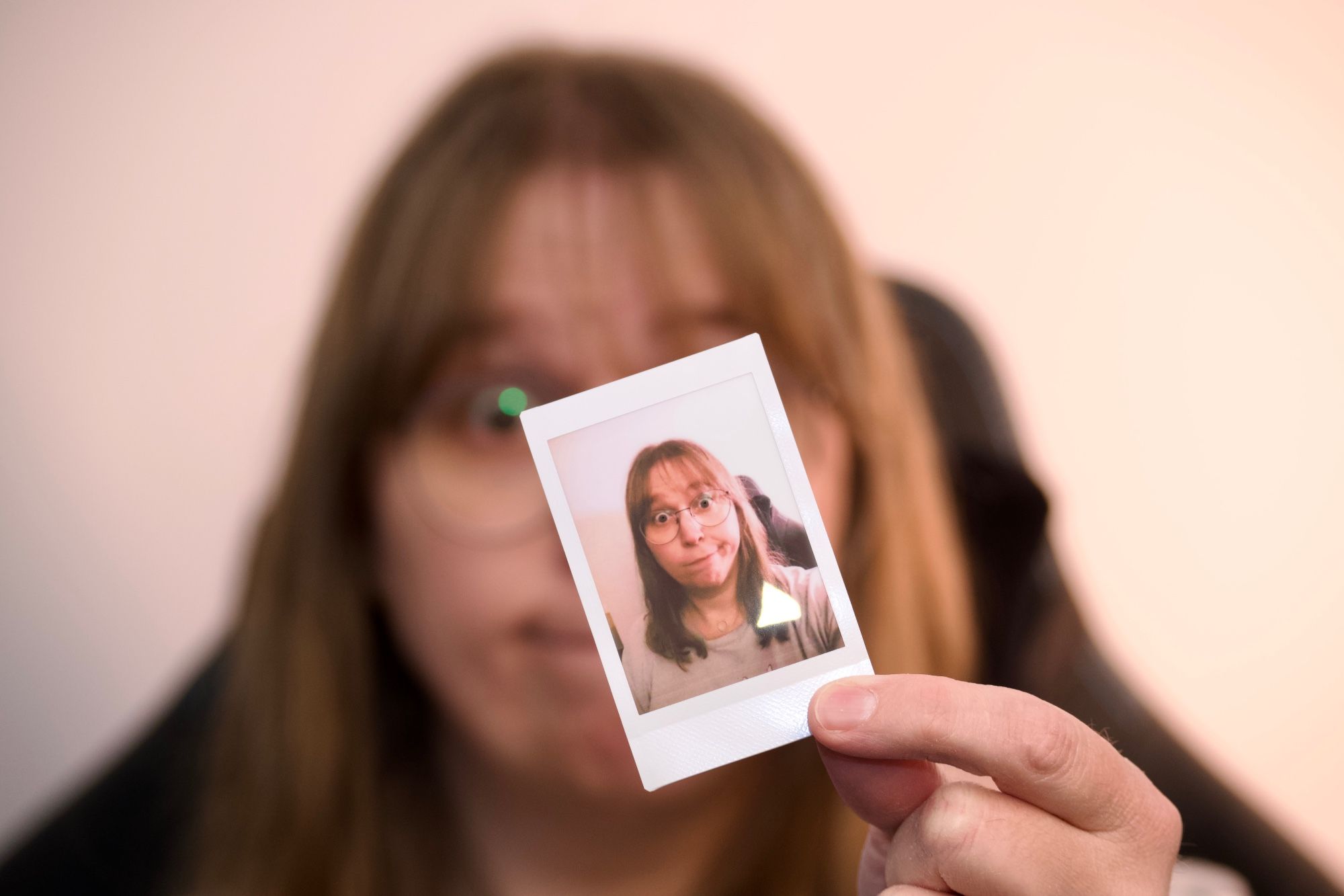 Person holding an Instax film exposure, which depicts the holder.