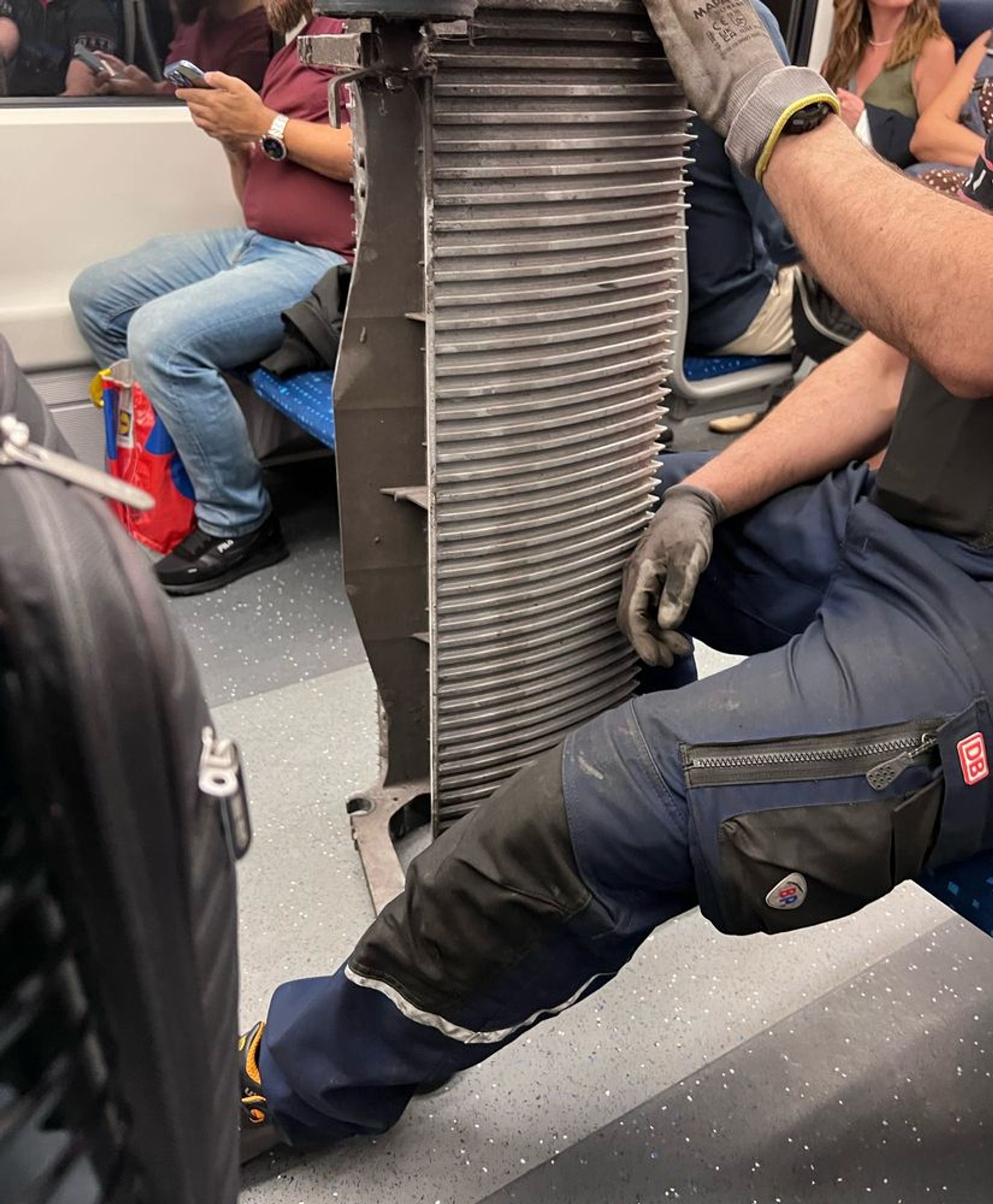 Ein Mann in der S-Bahn, der eine Rolltreppenstufe dabei hat. 