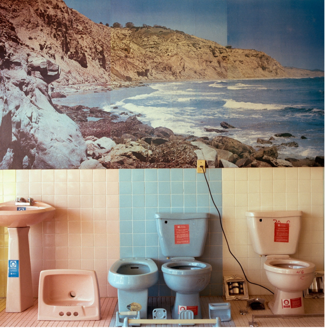 Upper part : photo of a rocky seaside.
Under : pink toilets, blue toilets, pink toilets.