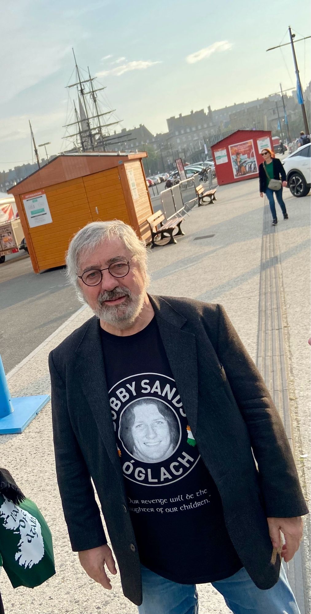 Sorj Chalandon sur un quai à Saint-Malo. Il regarde l'objectif et porte un t-shirt à l'effigie de Bobby Sands.