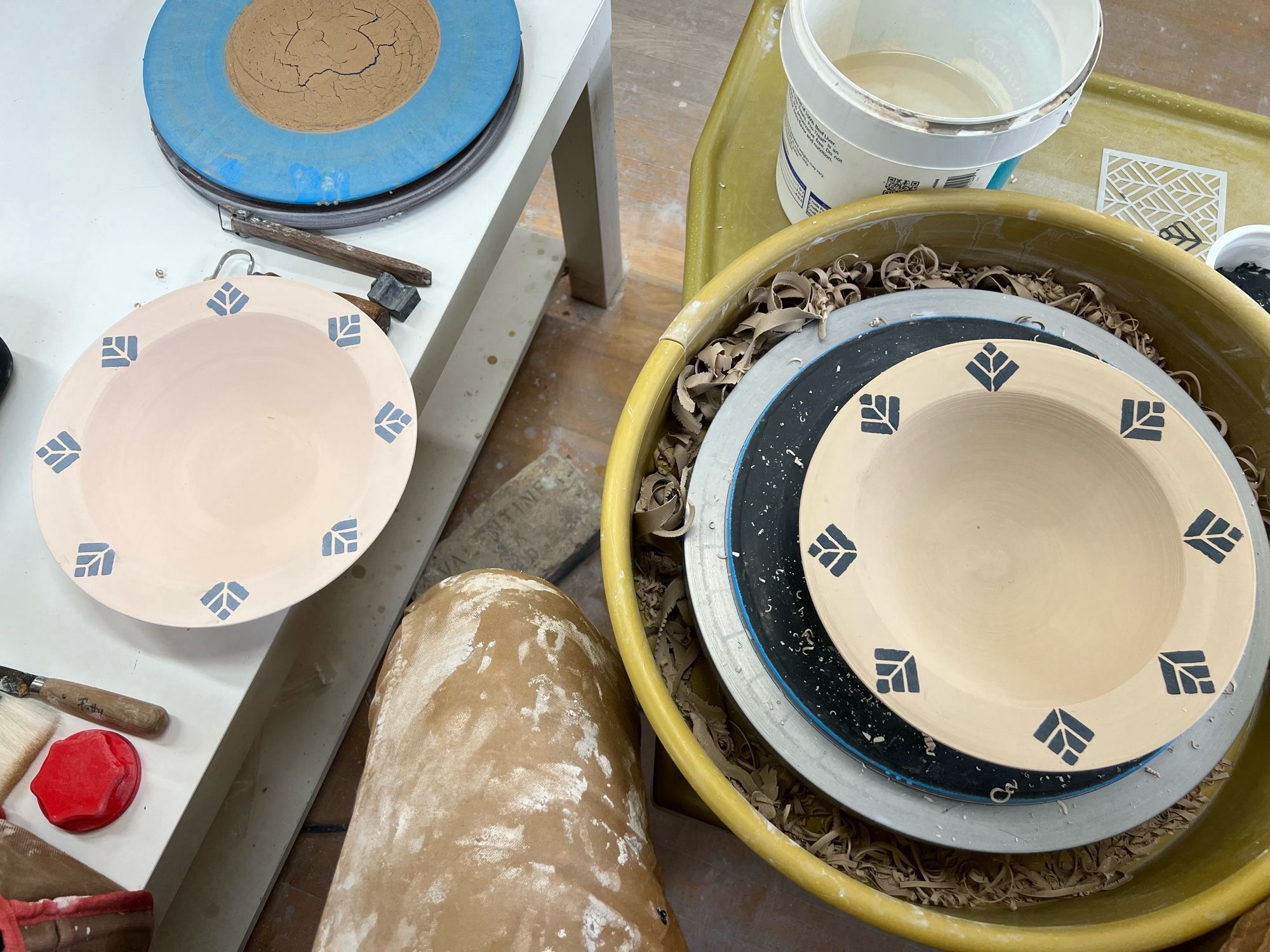 Two handmade pottery bowls with flat rims, each having 8 art deco diamonds applied to the rim with slip. The one on the left is bisque fired and the one on the right is still greenware.