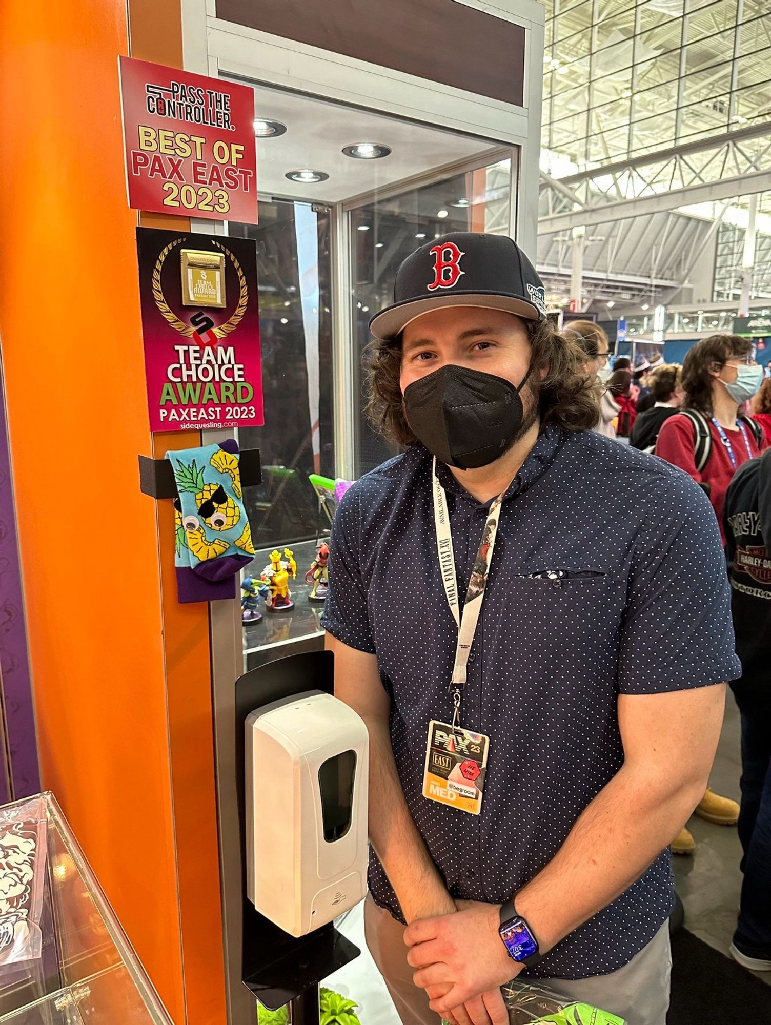 Brenda standing at the Yacht Club Games booth at PAX East 2023 next to their Best of PAX award for Mina The Hollower.