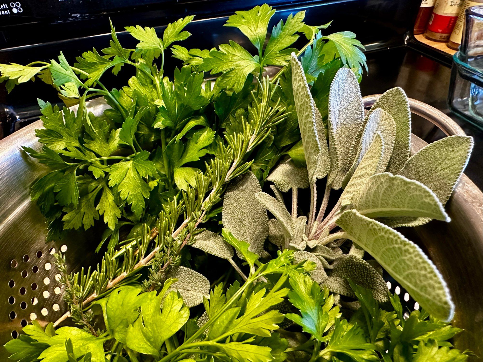 A colander full of parsley, sage, rosemary and thyme.